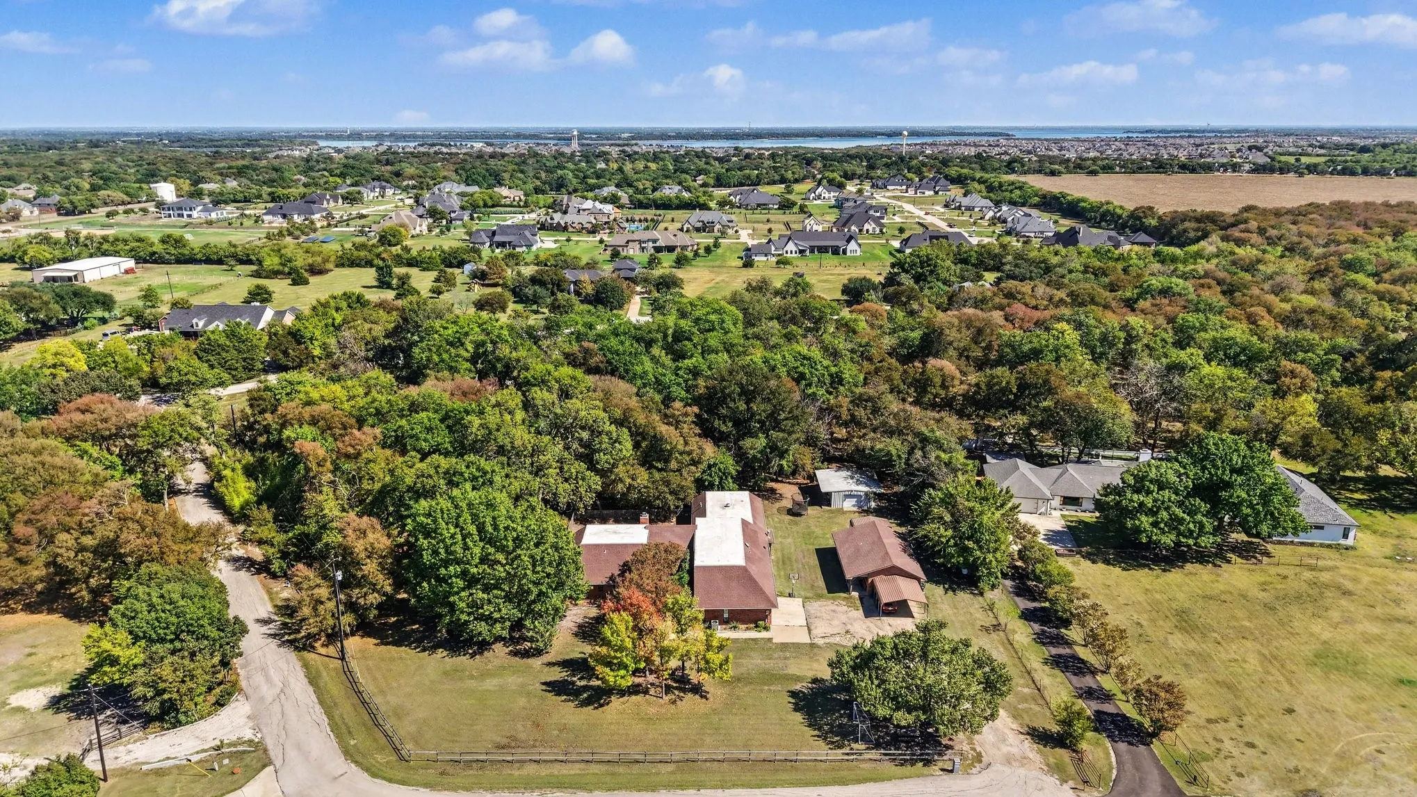 Expansive property featuring a treed landscape, a paved driveway, and multiple structures