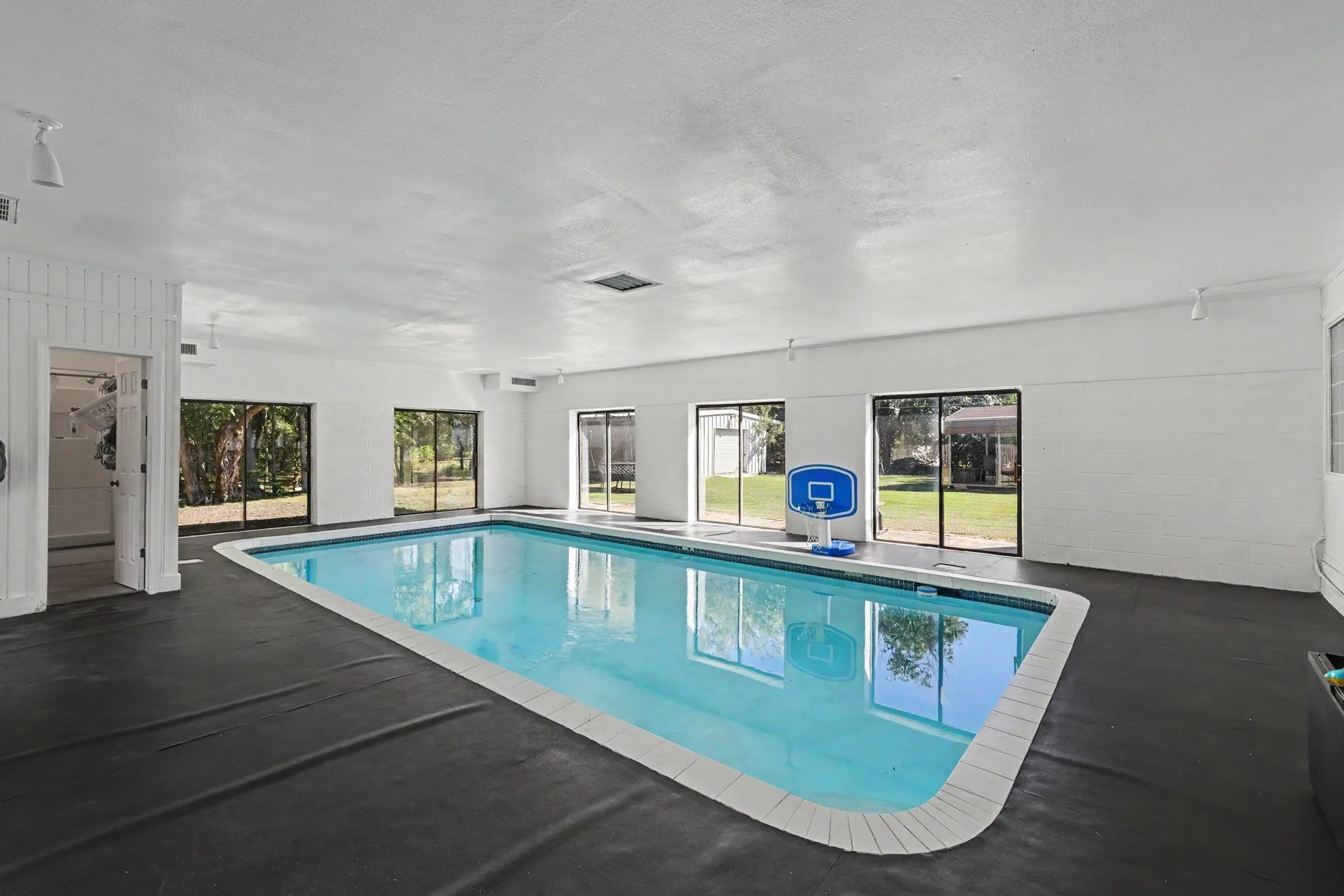 Indoor swimming pool with direct outdoor access, perimeter deck, and multiple windows