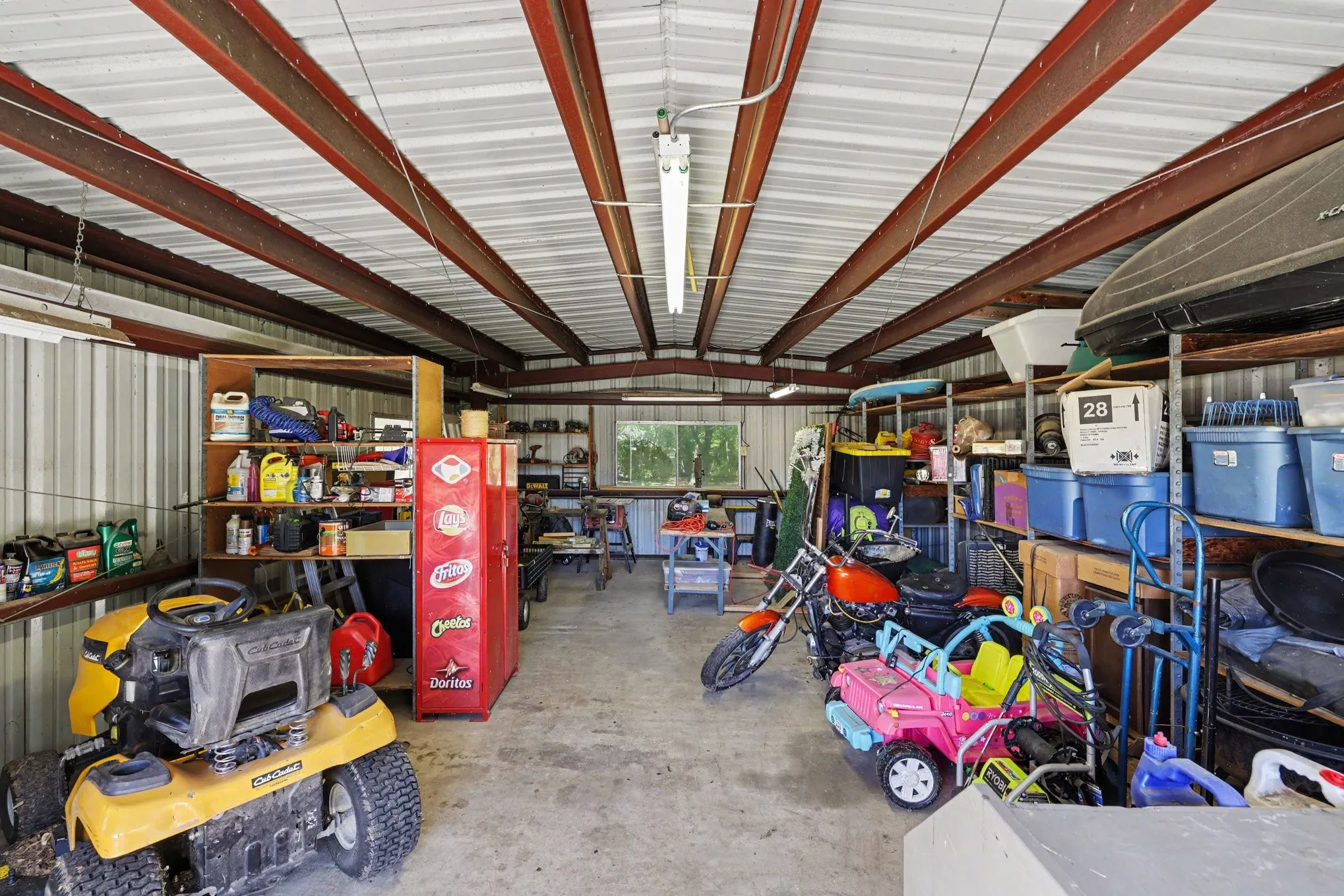Metal-clad structure with exposed steel beam ceiling, concrete flooring, built-in shelving, and transom window