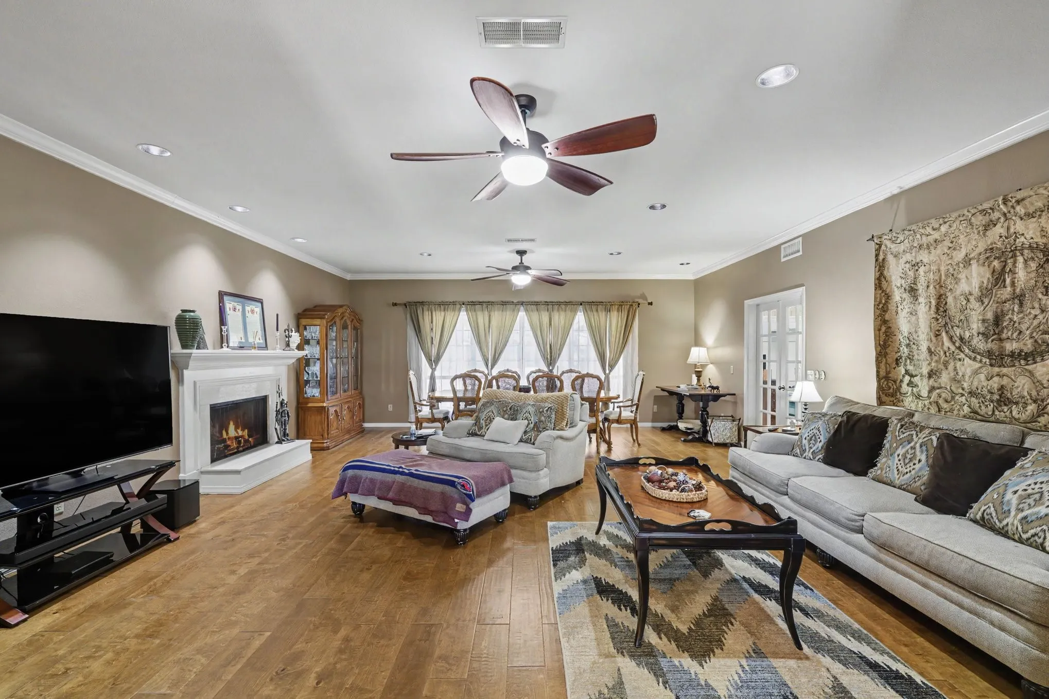 Spacious living area featuring wood-finish flooring, a white mantel fireplace, and recessed lighting