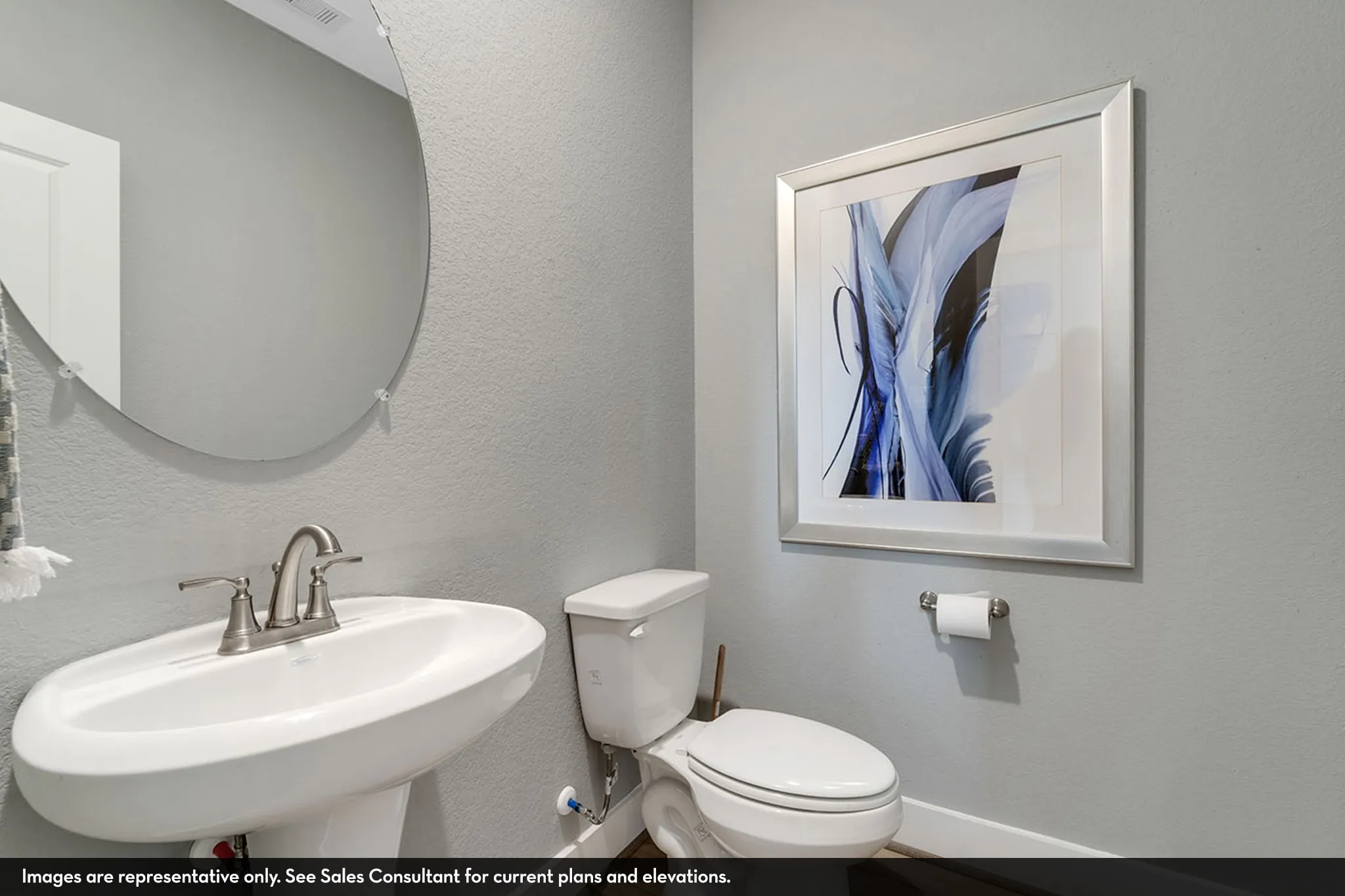 Pedestal sink with brushed nickel faucet, circular frameless mirror, and light gray wall paint