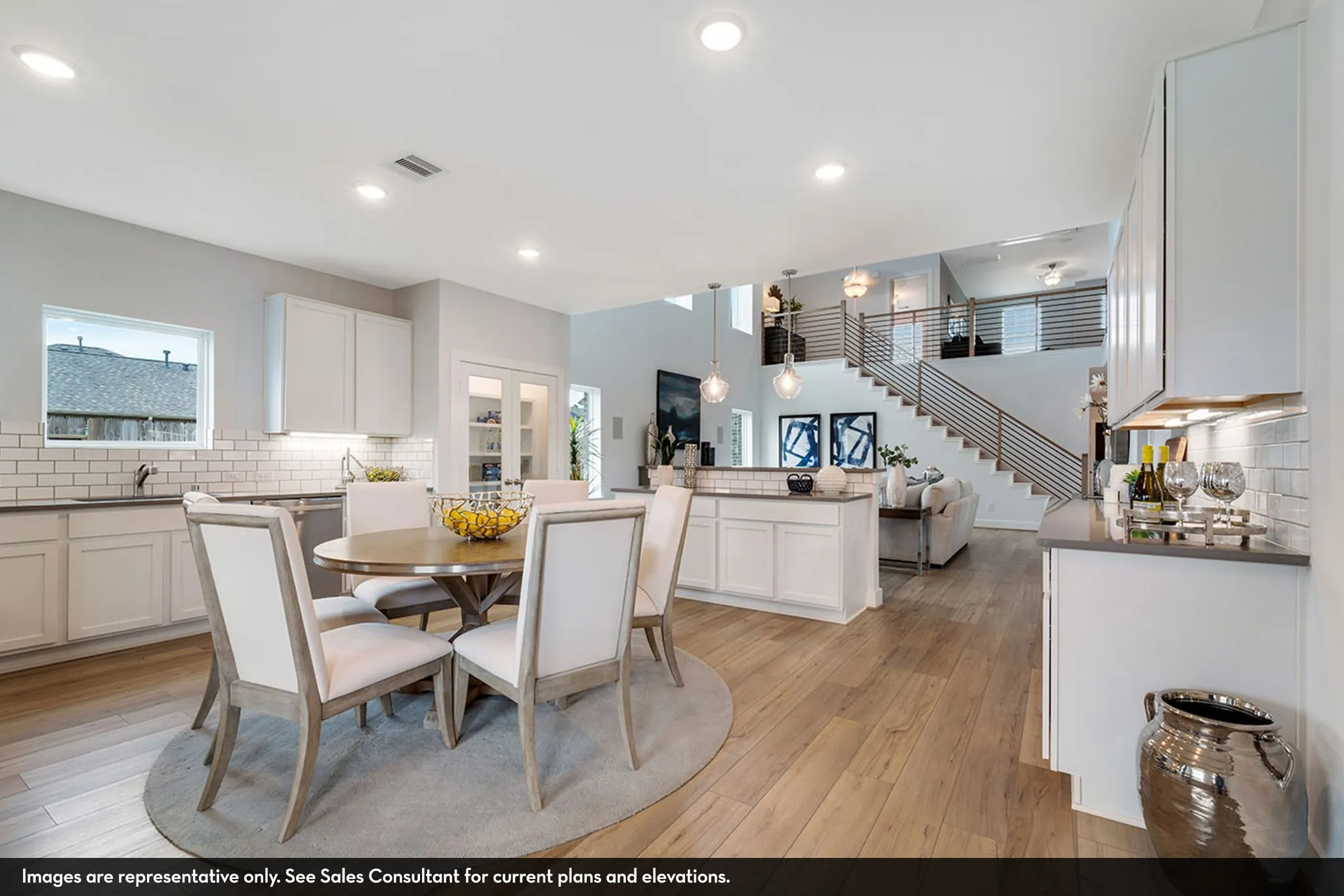 Open-concept living area featuring wood-finish flooring, a contemporary staircase with metal railings, recessed lighting, white shaker-style cabinetry, and subway tile backsplash