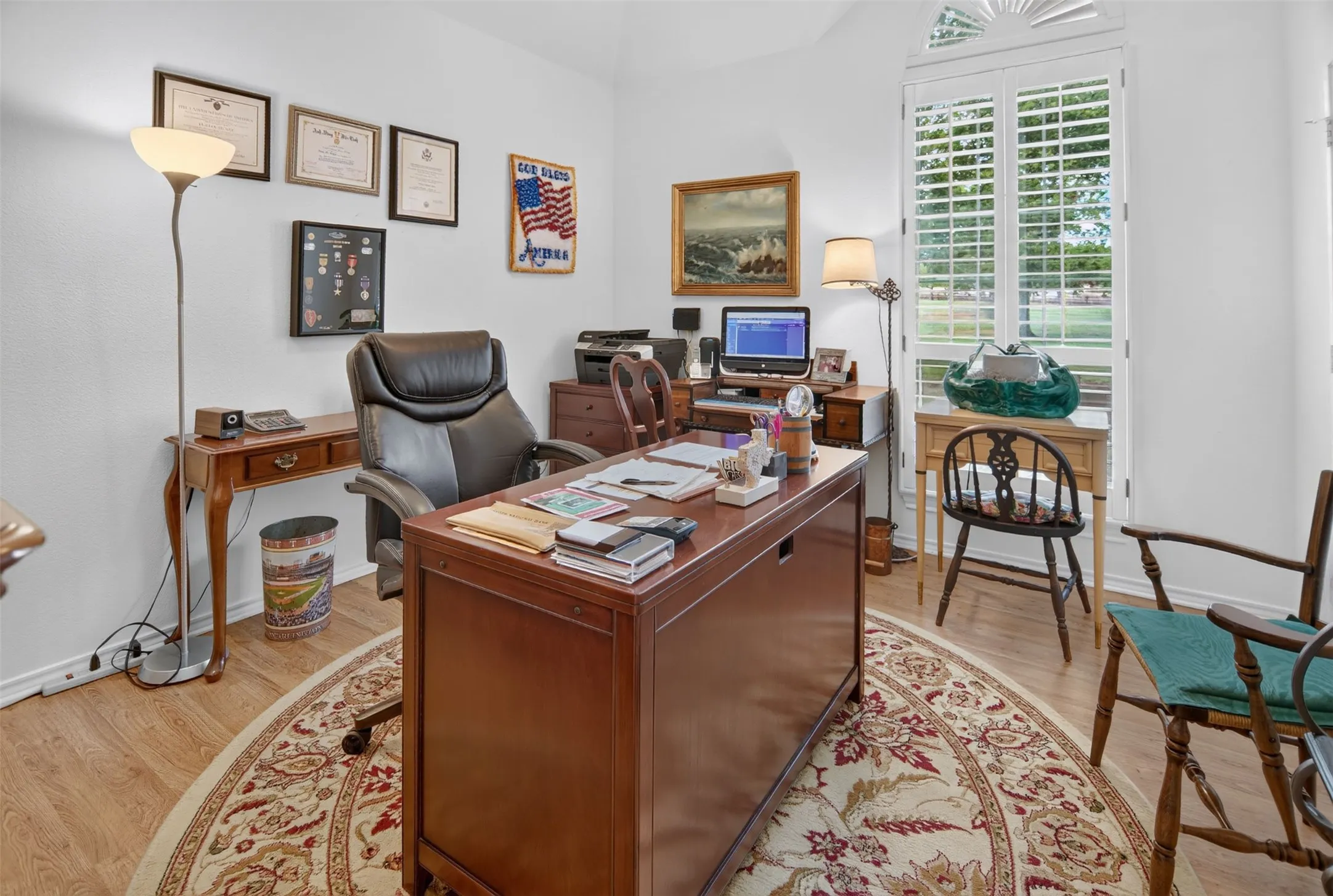 Wood-finish flooring, white walls, and a window with plantation shutters