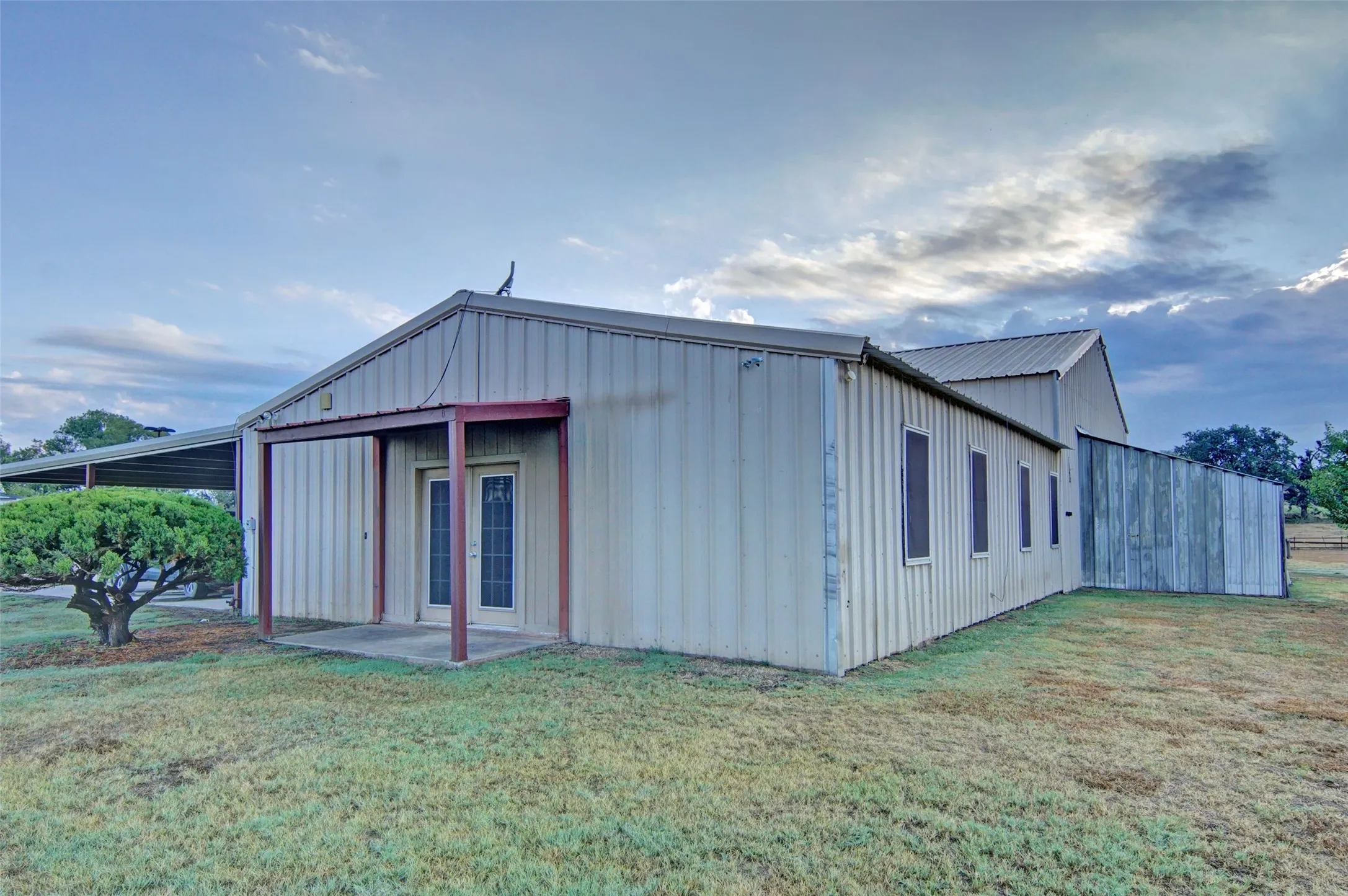 Metal-clad structure with a covered entry, a metal roof, and an attached carport