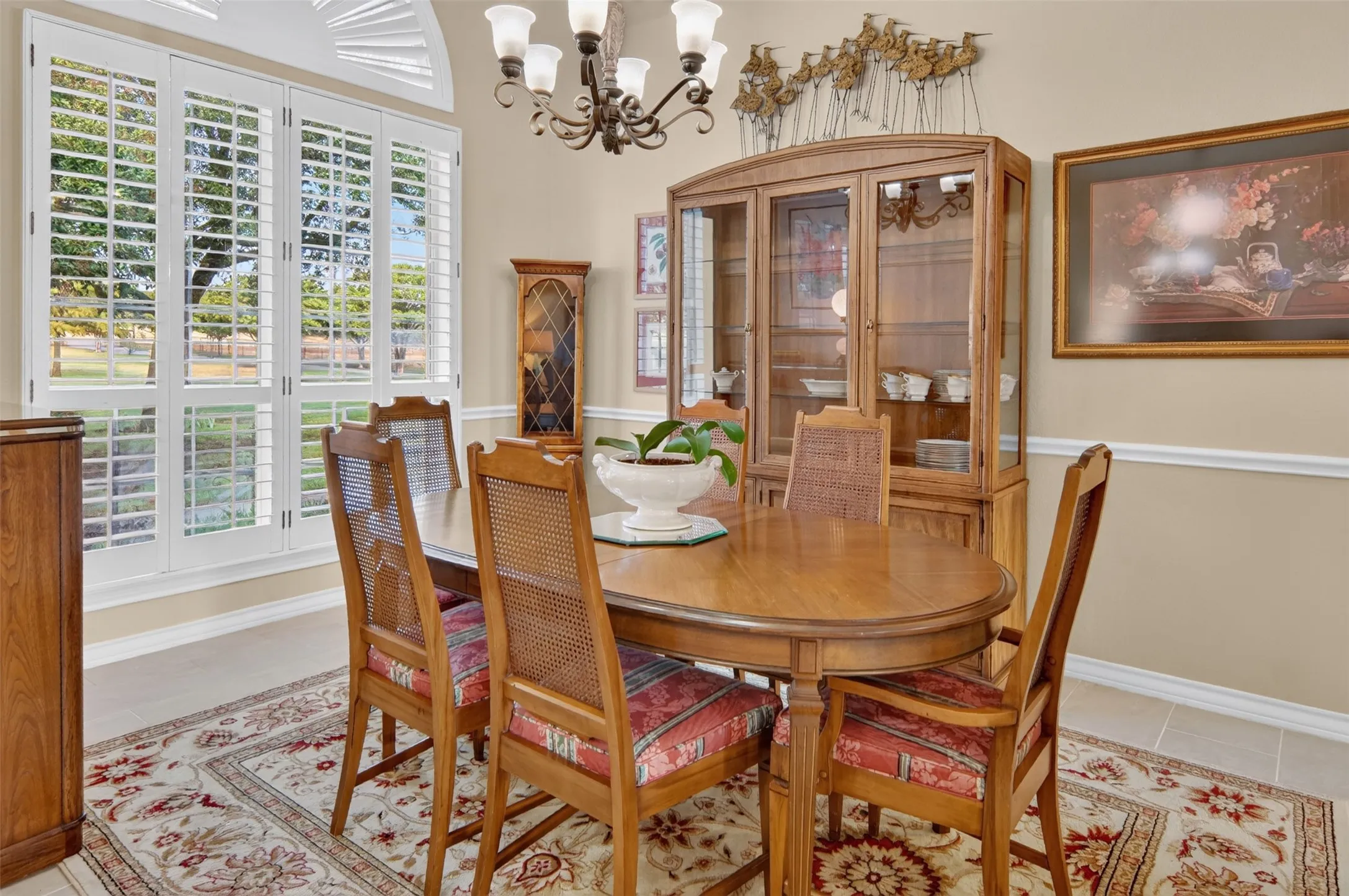 Recessed arched window with plantation shutters, crown molding, chair rail, and an ornate chandelier