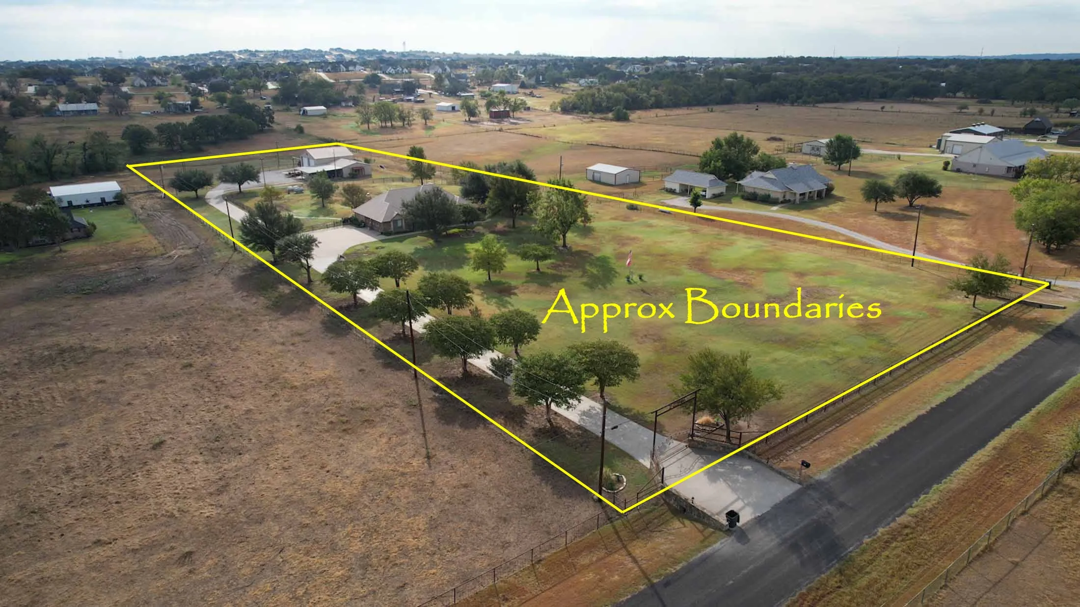 Expansive rural property offering approximately [acreage] with mature tree-lined perimeter, established landscaping throughout the grounds, paved driveway access, and multiple outbuildings