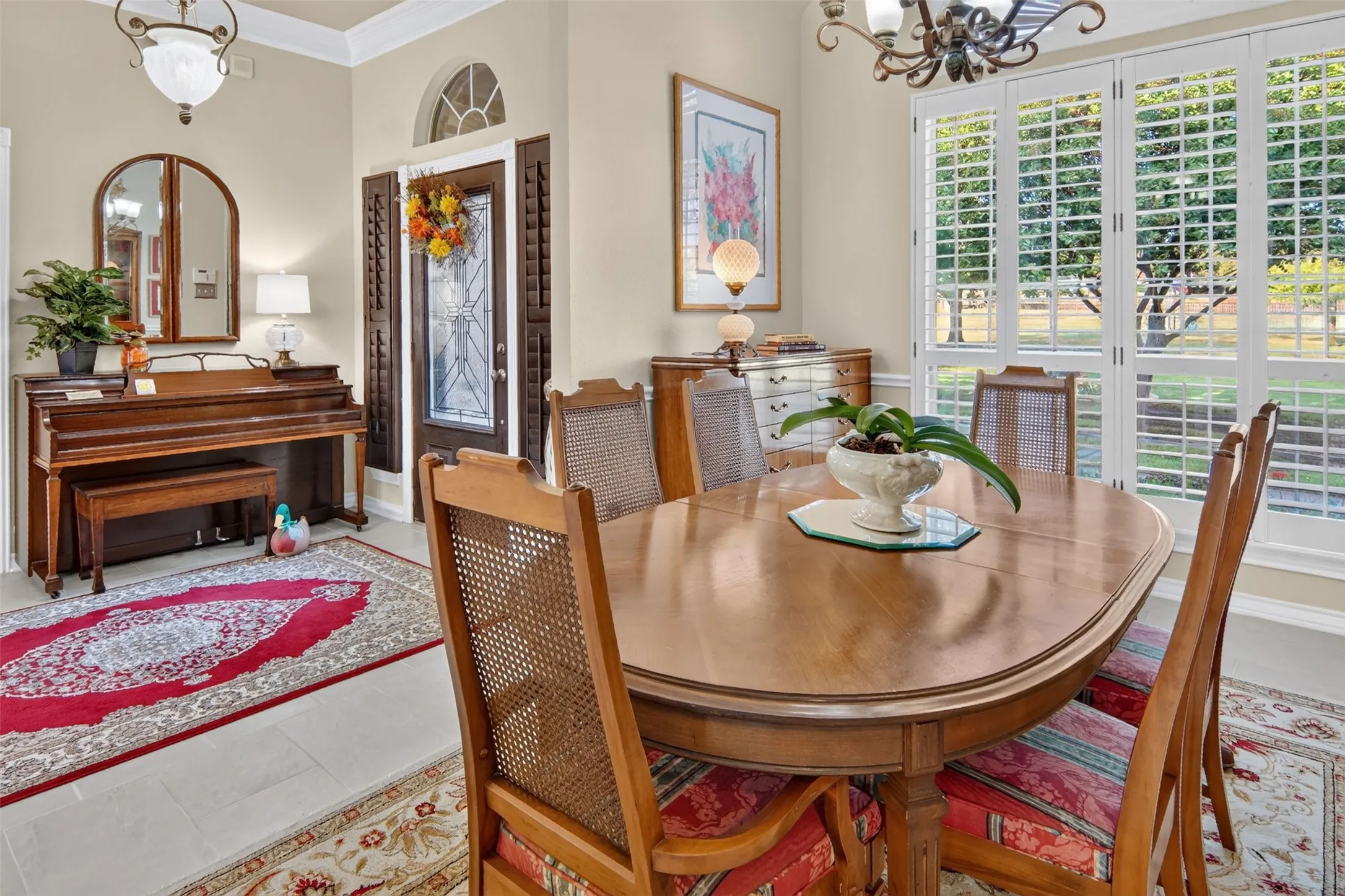 Window shutters, arched entryway, decorative glass panel door, light tile flooring, crown molding