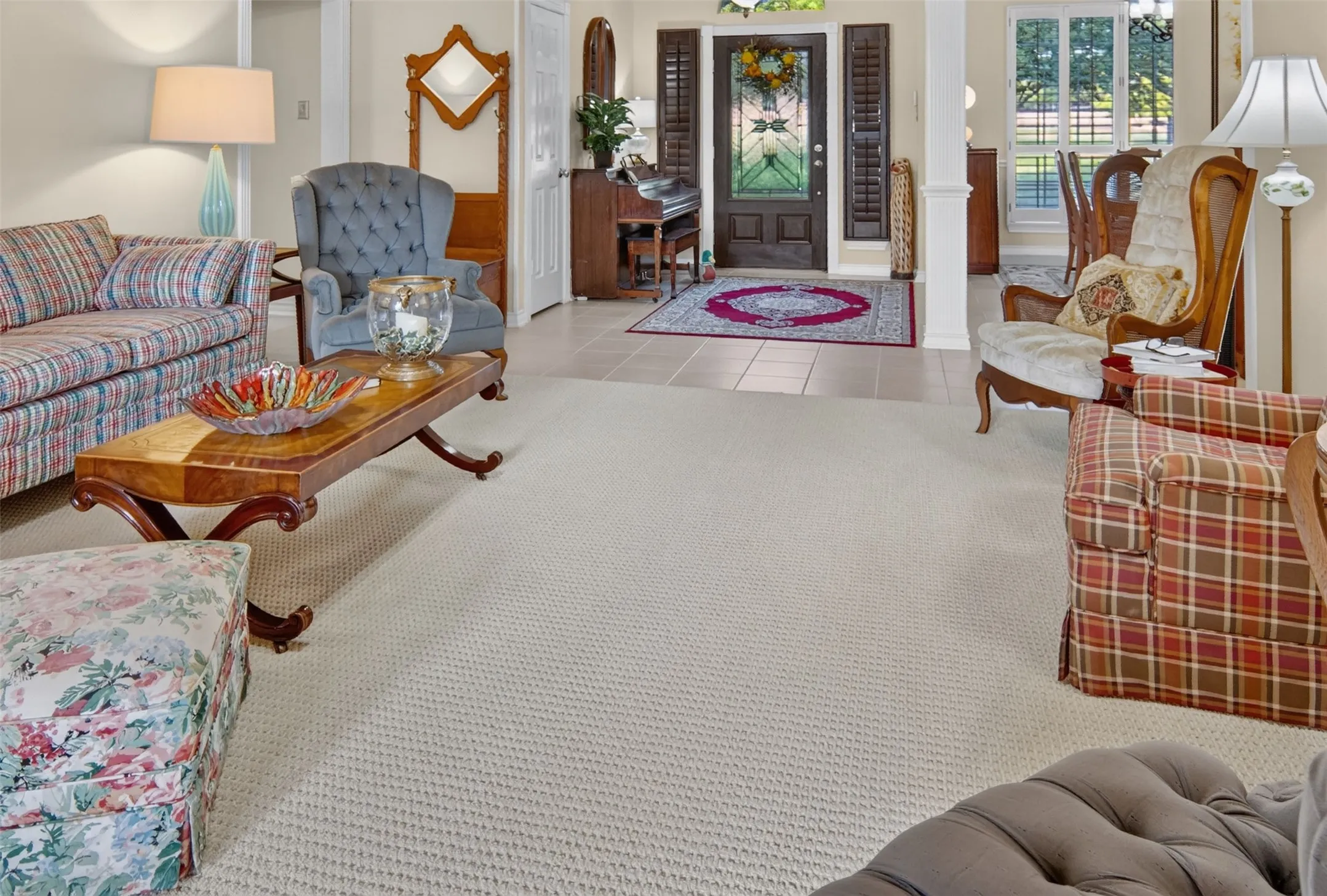 Light-toned carpeted flooring throughout, tile entry, and architectural columns