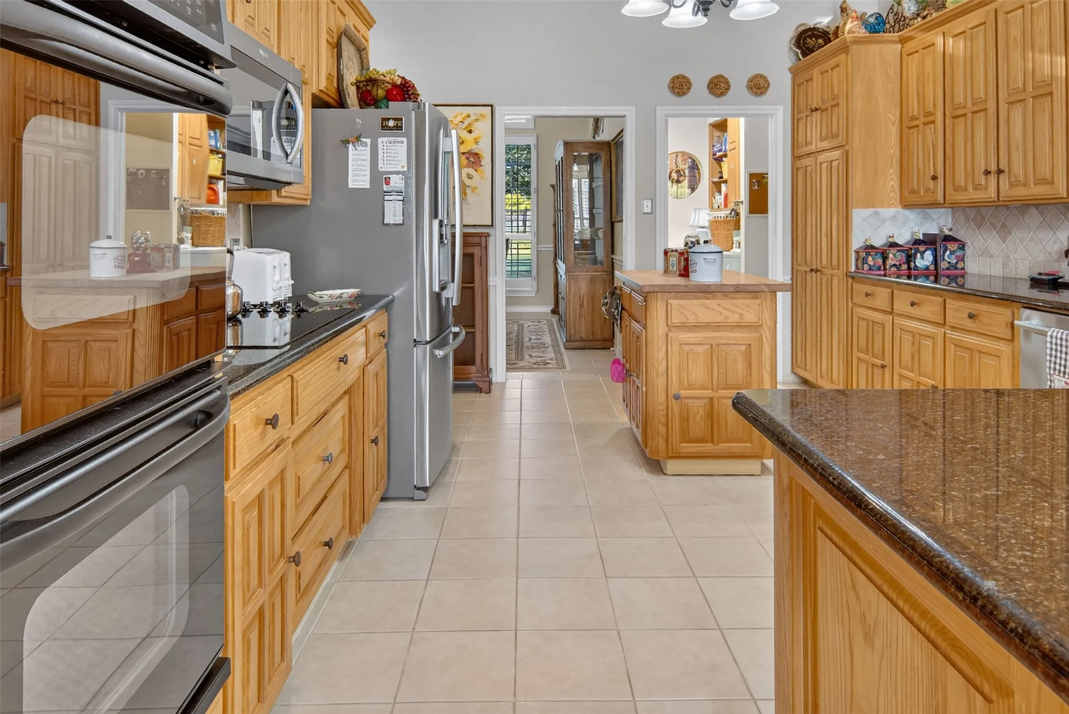 Kitchen featuring wood cabinetry, stainless steel appliances, dark stone countertops, and a tile floor