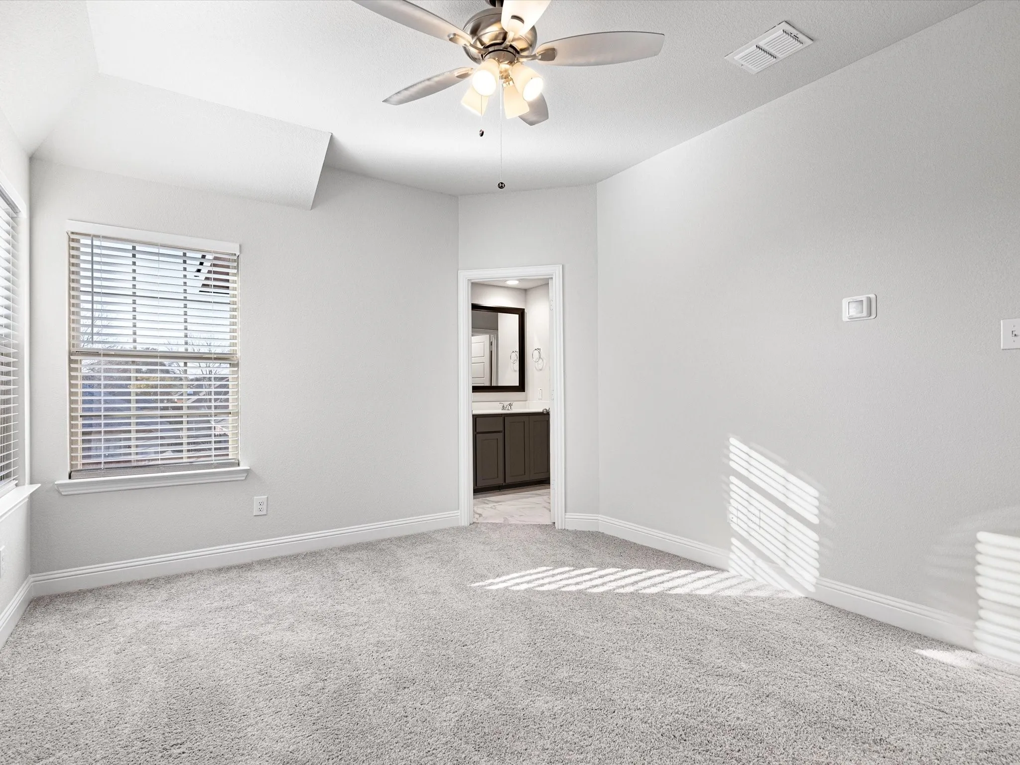 Carpeted room featuring a ceiling fan, window with blinds, and white baseboards
