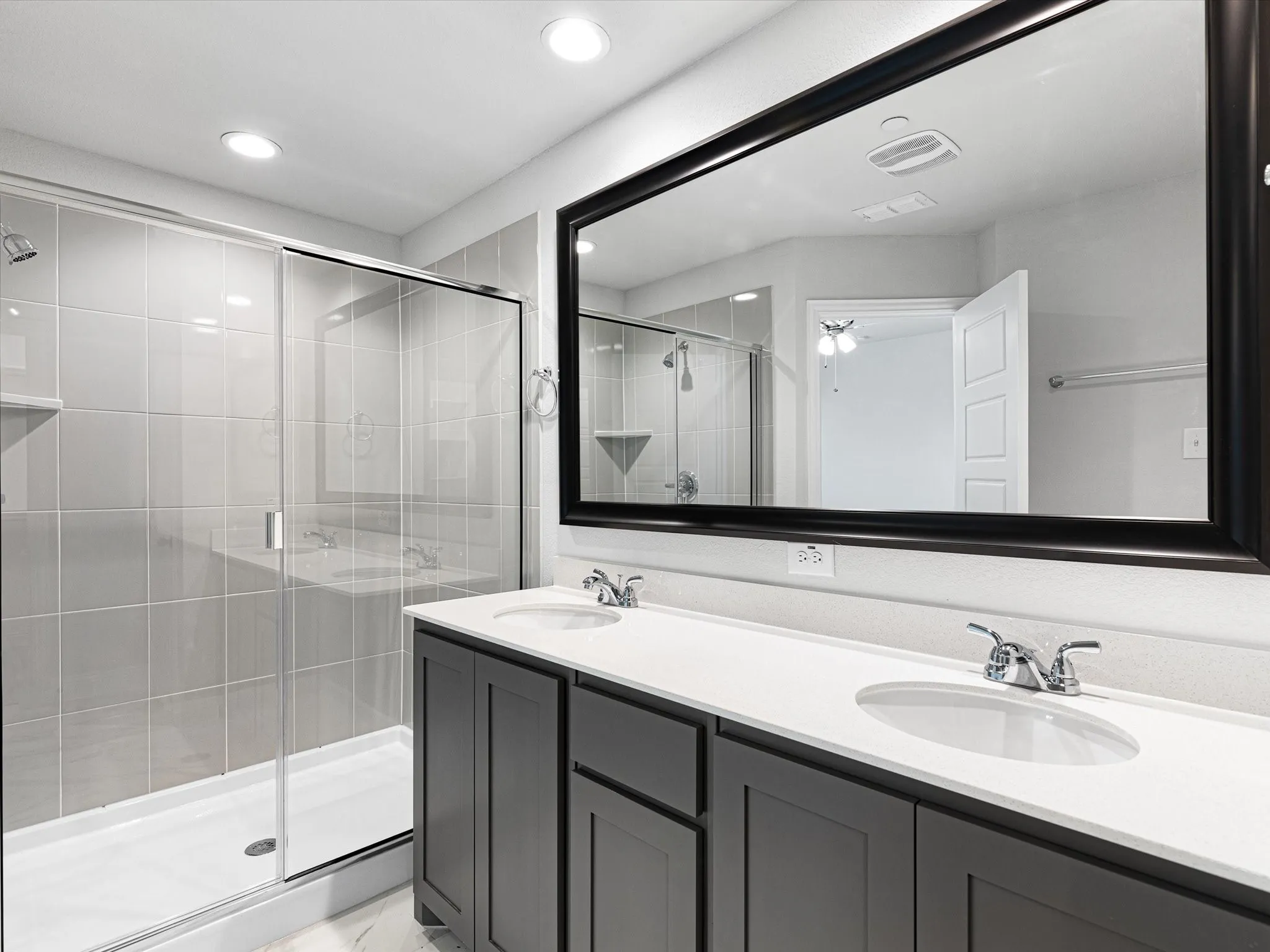 Dual vanity with white undermount sinks and dark cabinetry, set against a full-width framed mirror