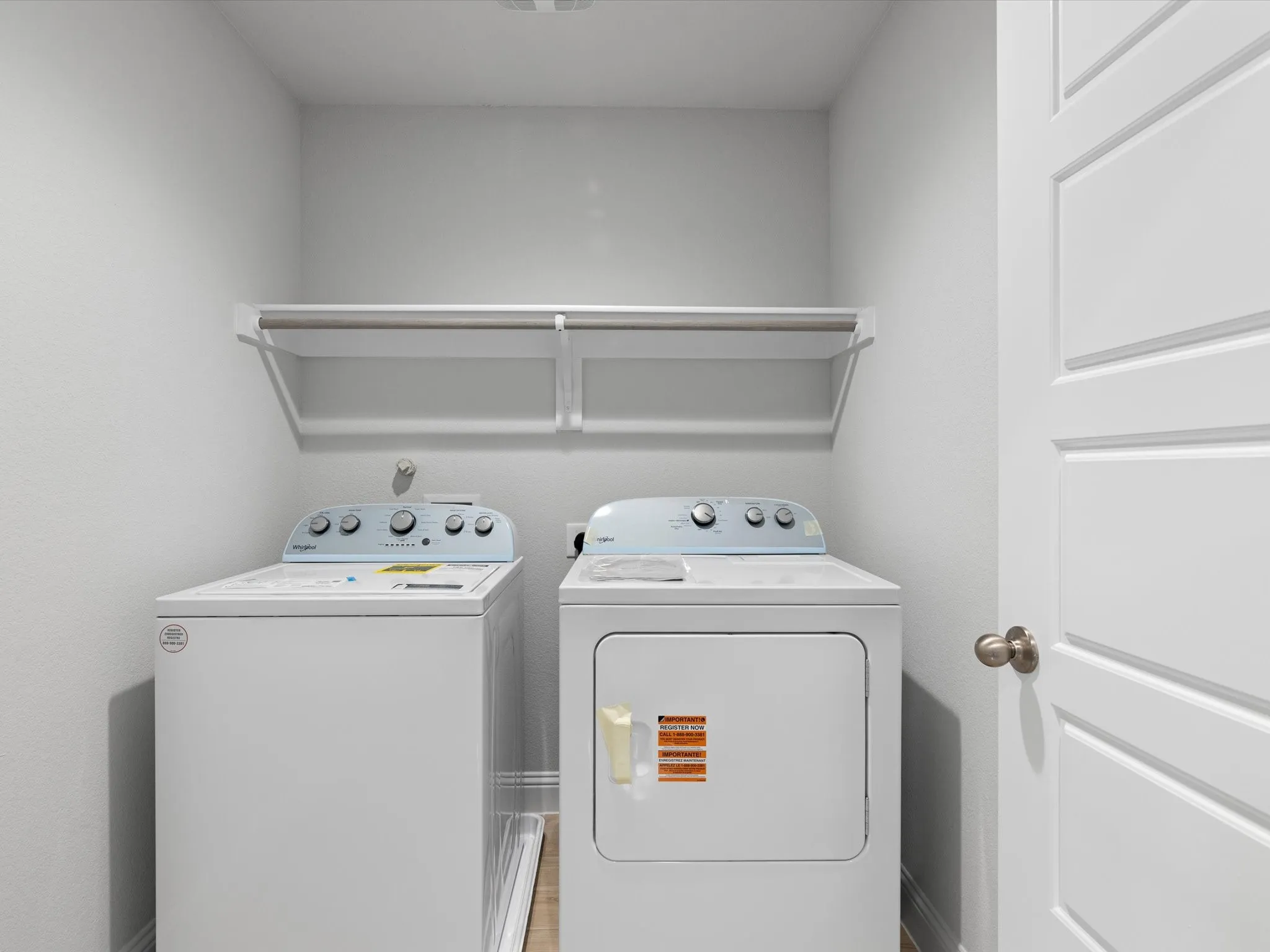 Dedicated laundry area with built-in shelving and light wood-finish flooring
