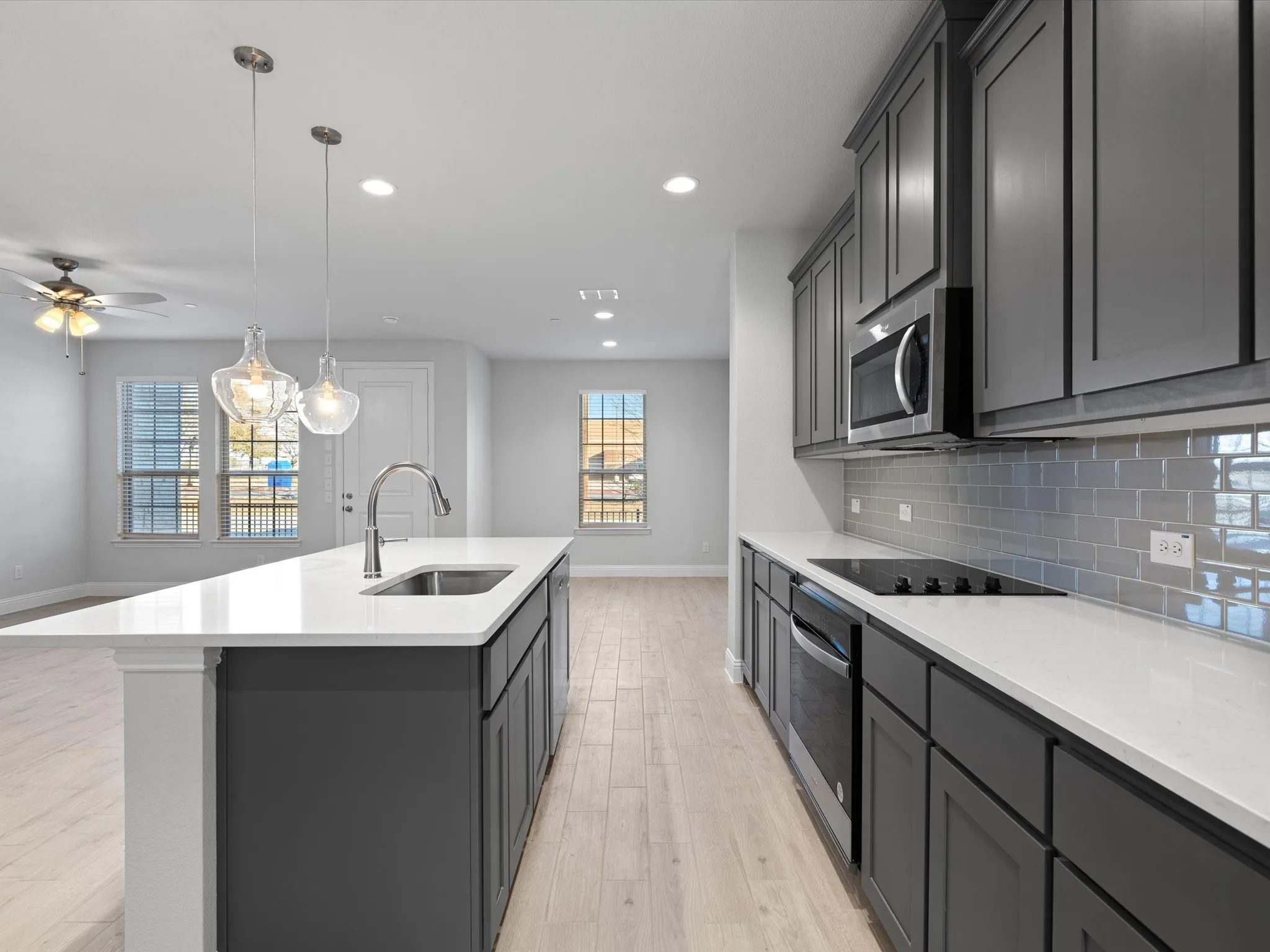 Kitchen featuring wood-finish flooring, shaker-style cabinetry, a built-in microwave, and a subway tile backsplash