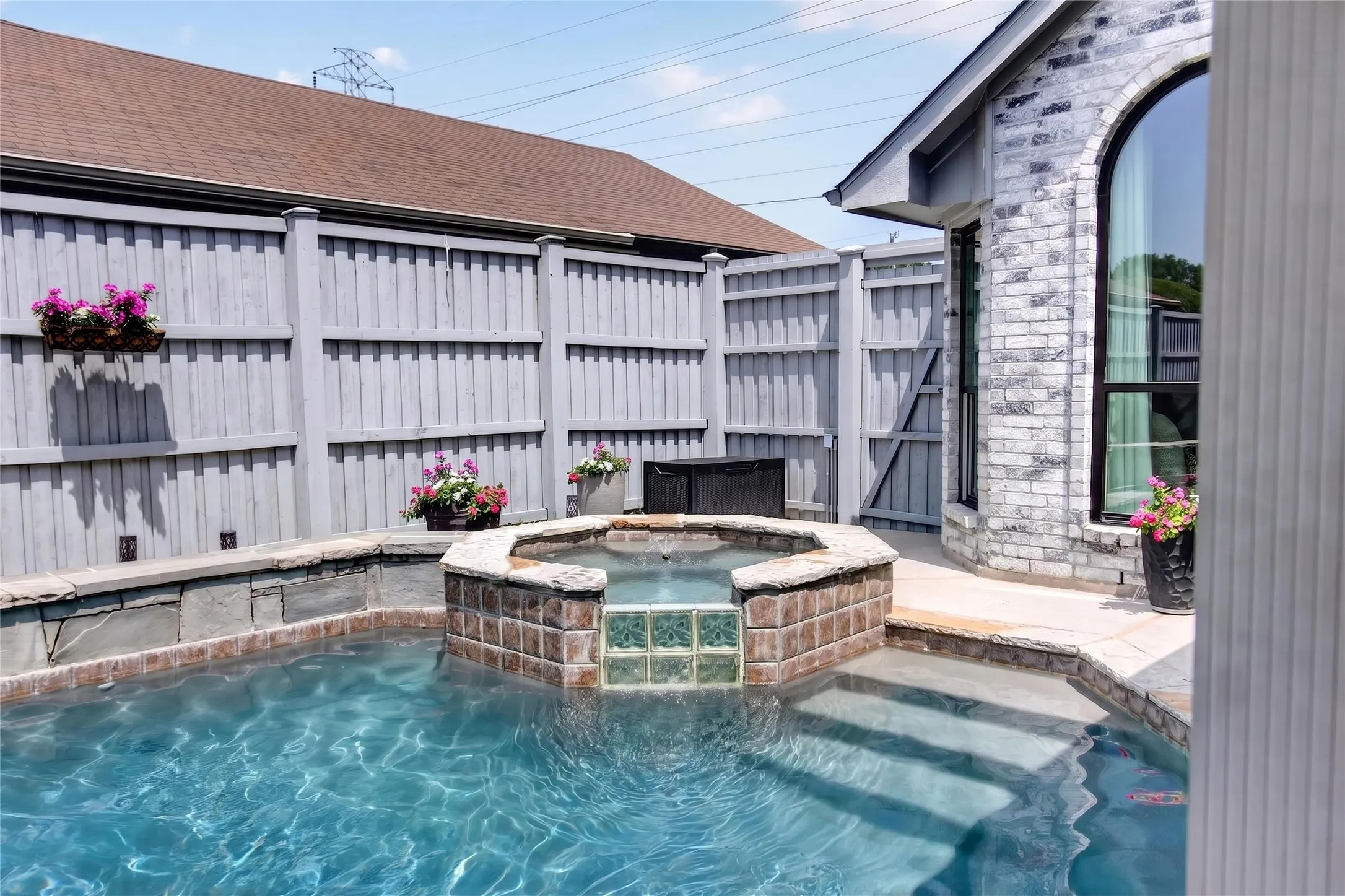 View of sparkling pool and spa. A premium board on board fence surrounds the backyard, providing a peaceful and secluded setting to unwind or host family and friends.