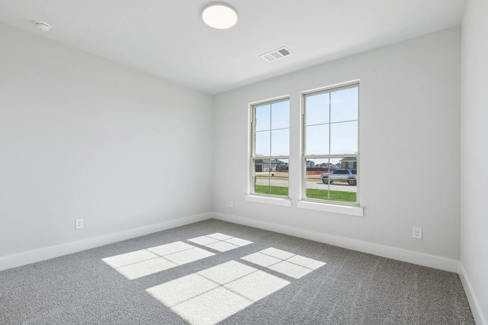 Light gray carpeted flooring, white painted walls, and twin double-hung windows
