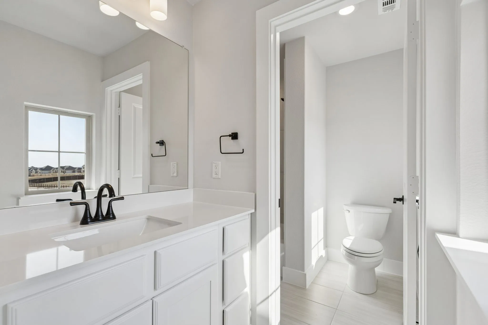 White vanity with integrated sink, black faucet, and a large wall-mounted mirror