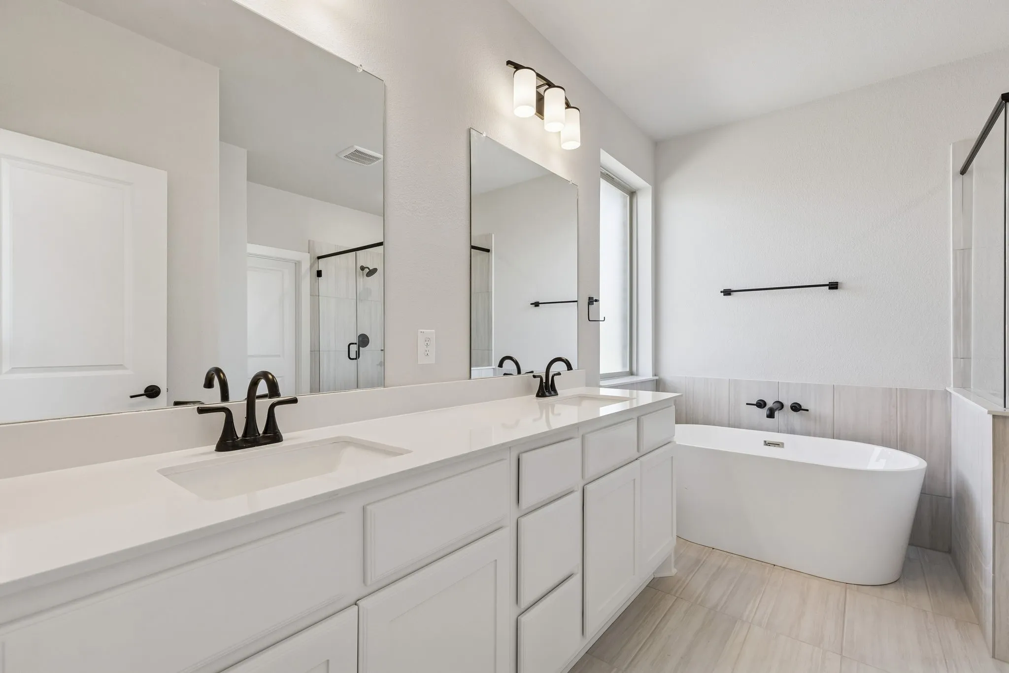 Dual vanity with undermount sinks, white cabinetry, and matte black fixtures