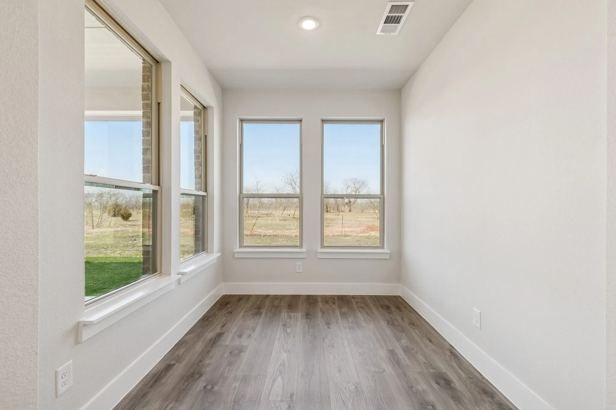 Multiple windows, wood-finish flooring, recessed lighting, and white walls