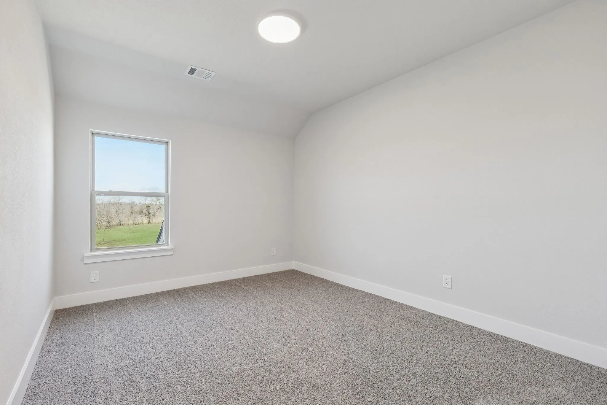 Carpeted room featuring a single window and a ceiling-mounted light fixture