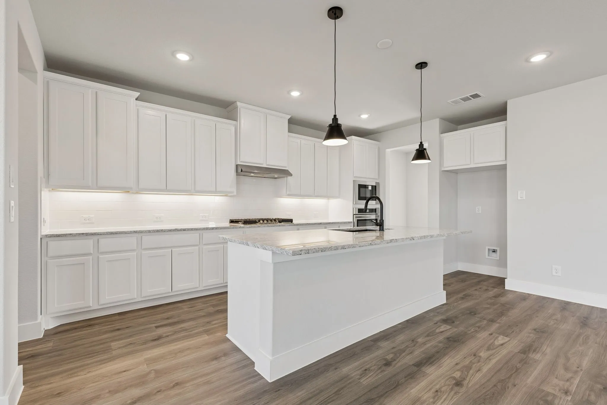 Kitchen featuring a central island with countertop, white cabinetry, wood-finish flooring, recessed lighting, and pendant light fixtures