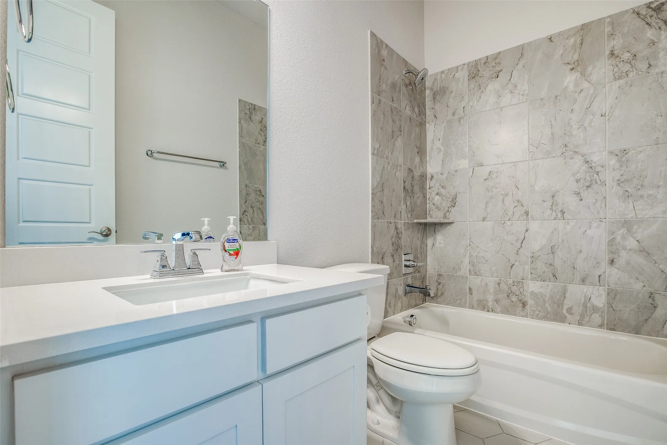 White vanity with an integrated sink and chrome faucet, white countertop, and framed mirror