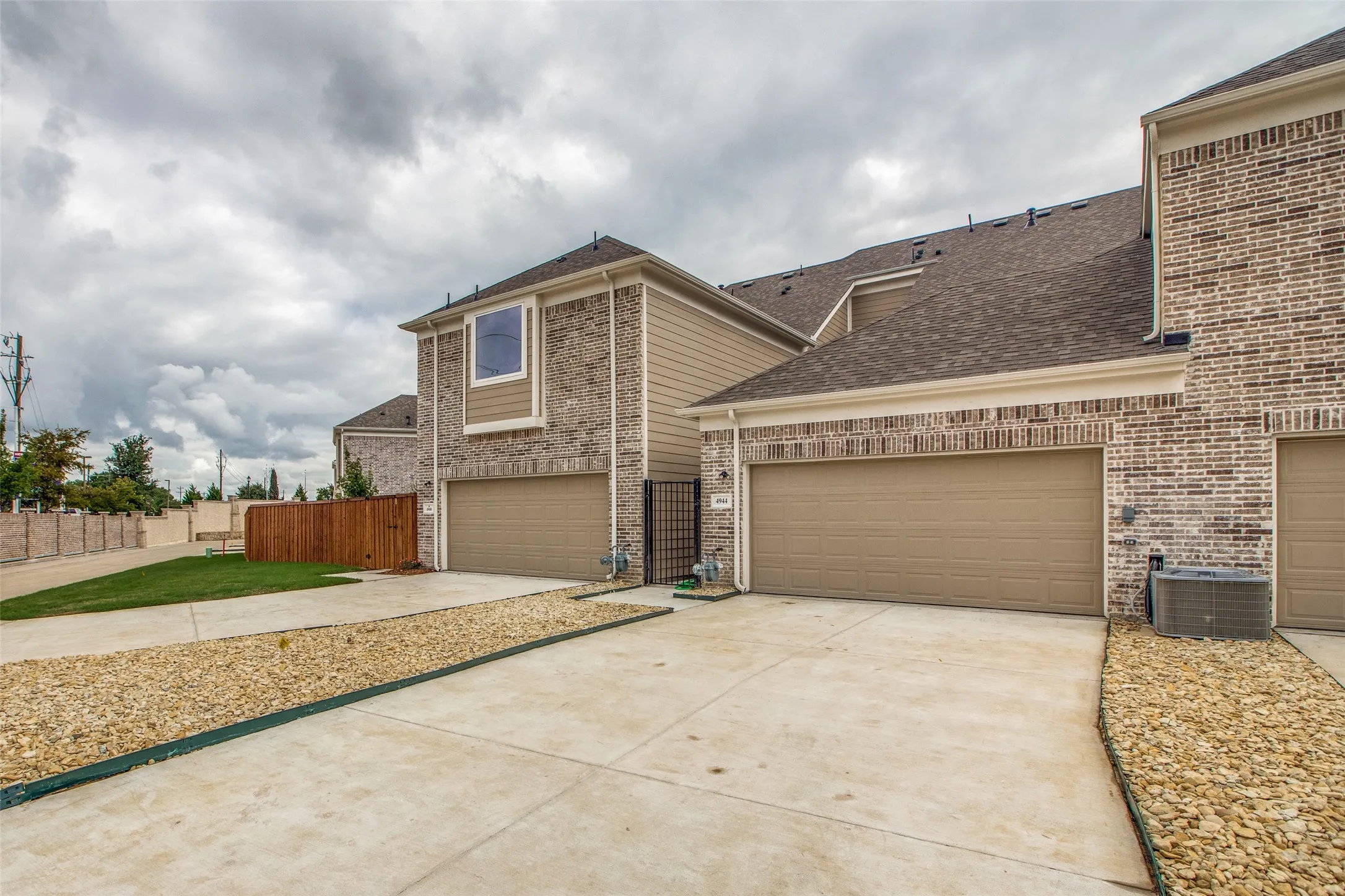 Brick and siding exterior, two-car garage, concrete driveway, and gravel landscaping