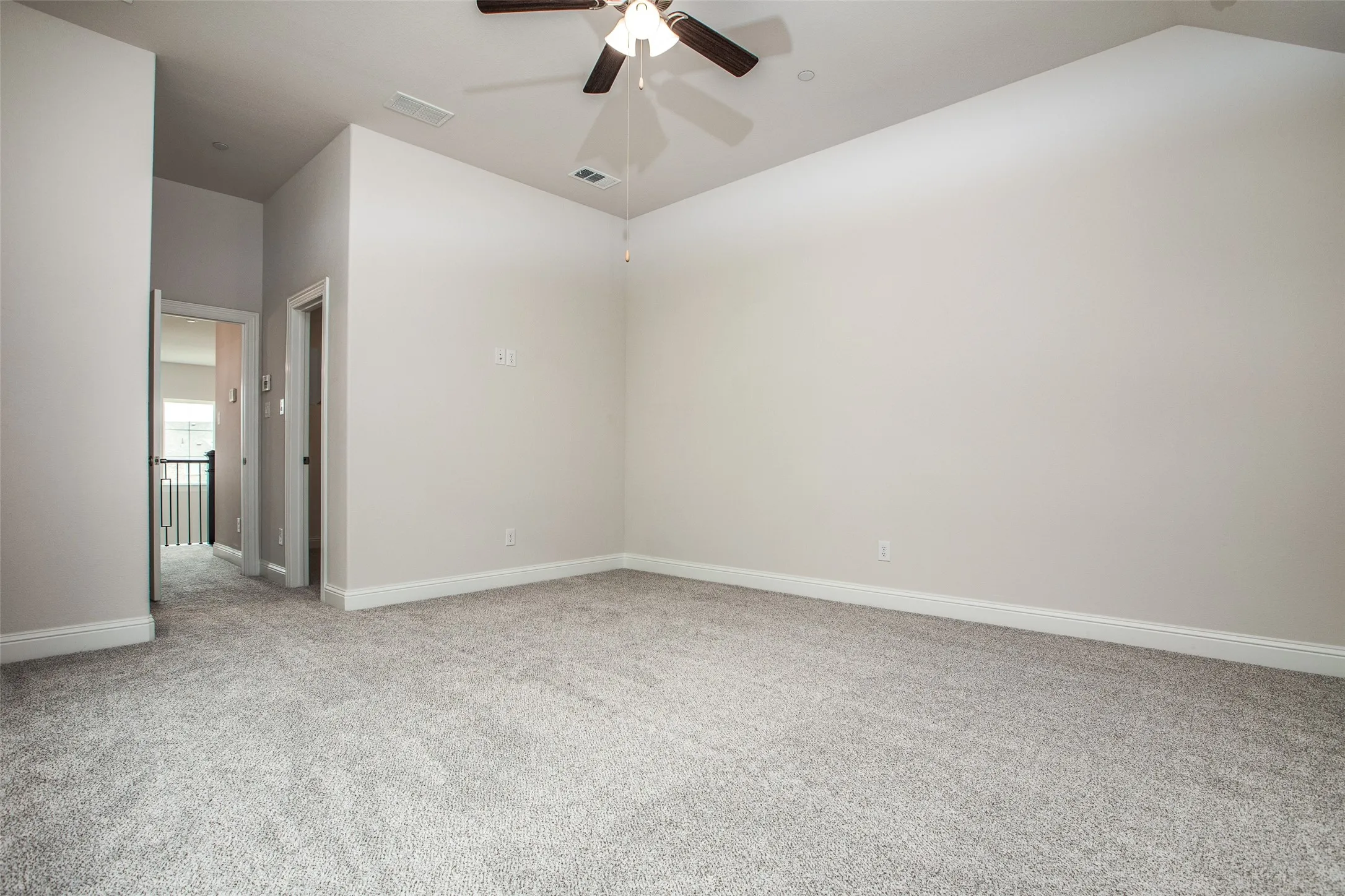 Spacious room with light neutral carpet, a ceiling fan with integrated lighting, and neutral wall paint