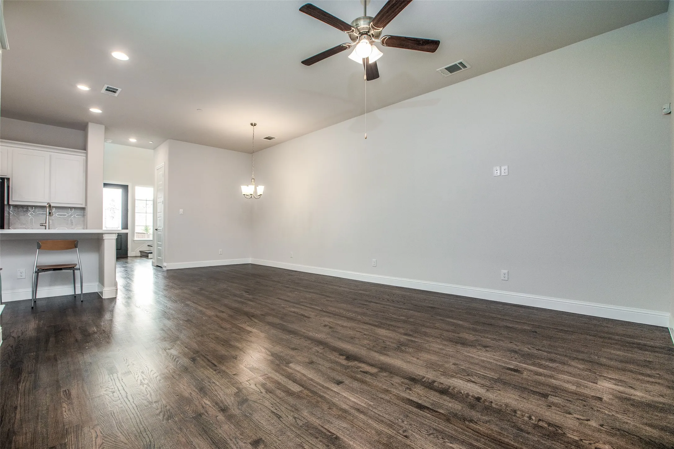 Expansive room featuring wood-finish flooring, a ceiling fan, recessed lighting, and a chandelier
