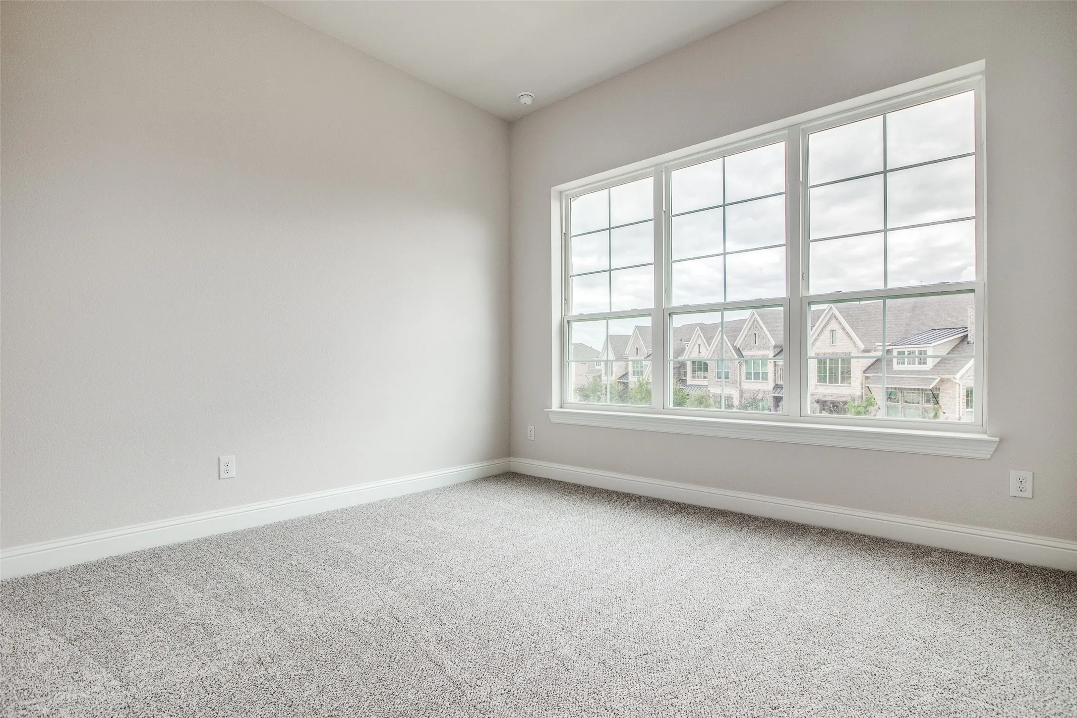 Recessed lighting, large multi-pane window, white window trim, gray wall-to-wall carpeting, and neutral wall paint