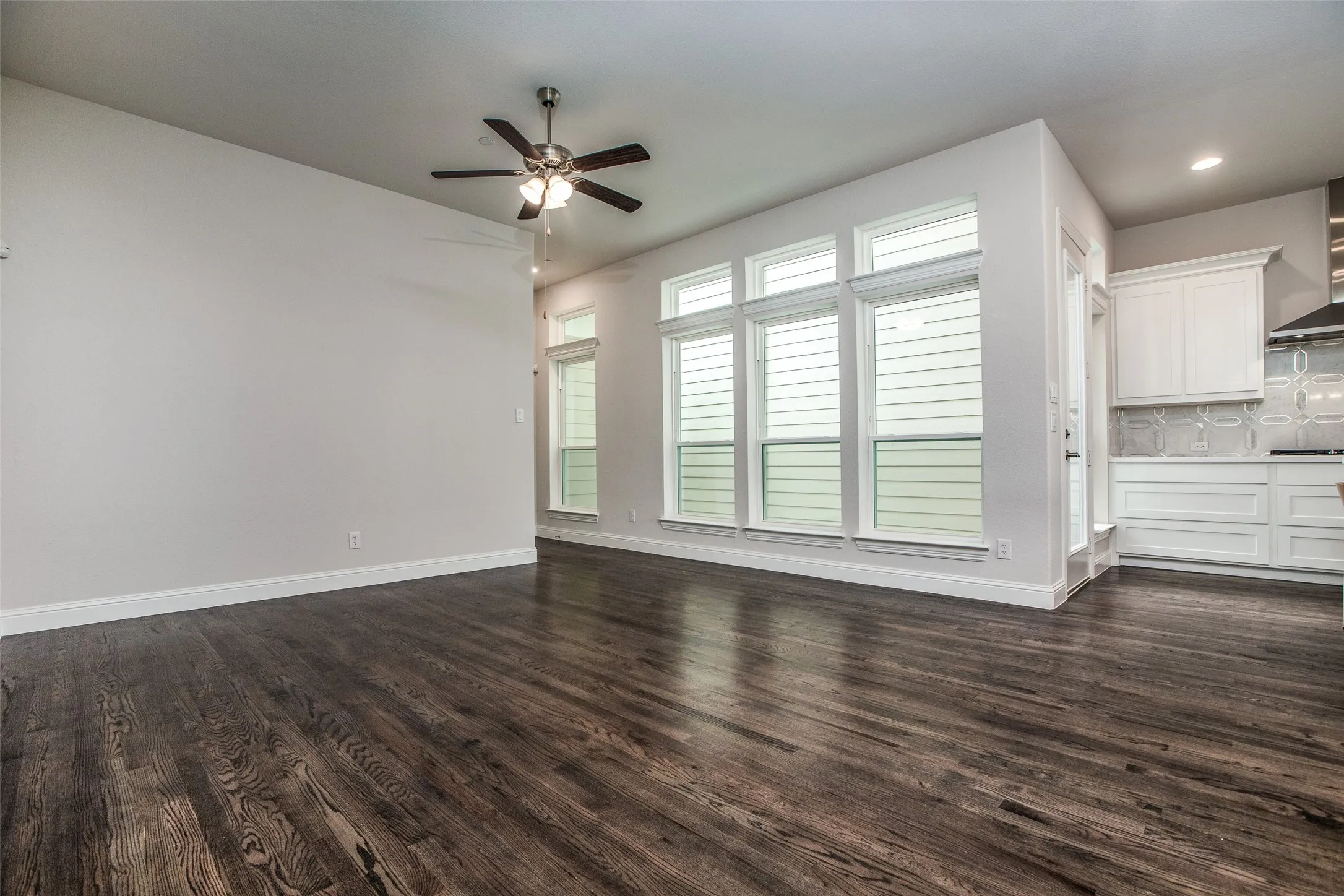 Wood-finish flooring, multiple windows, recessed lighting, ceiling fan, white cabinetry
