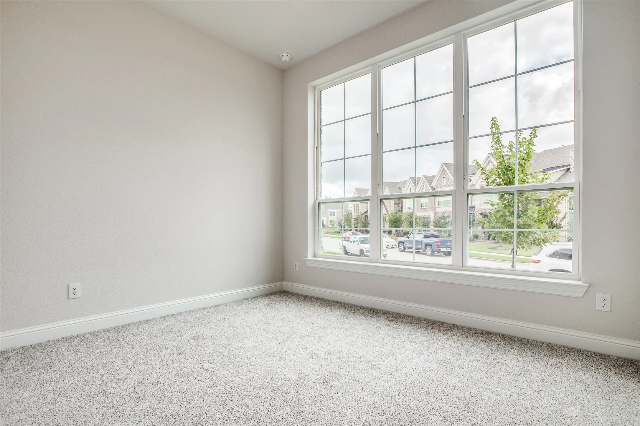 Expansive window wall with grid pattern, neutral gray wall finish, recessed lighting, and light-toned carpet