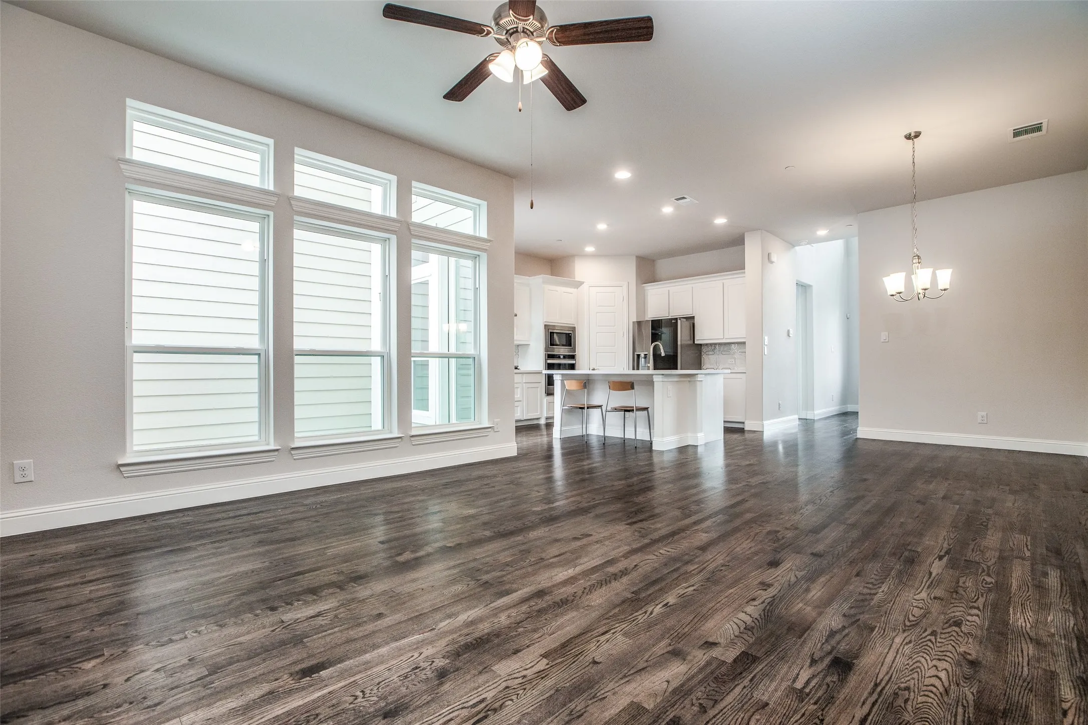 Expansive wood-finish flooring throughout, featuring a wall of multi-pane windows with white trim