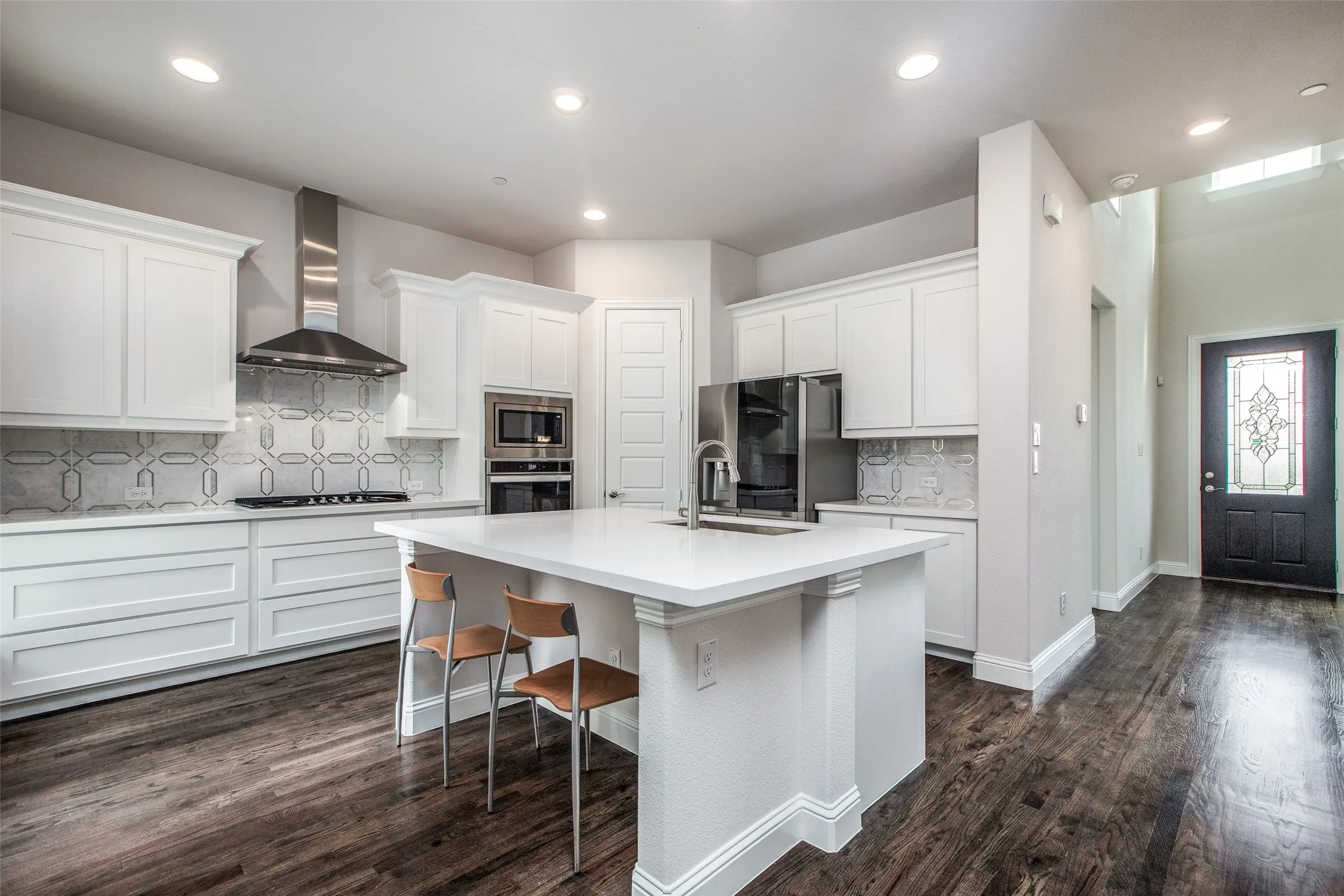 Kitchen featuring white cabinetry, stainless steel appliances, a center island with seating, and wood-finish flooring