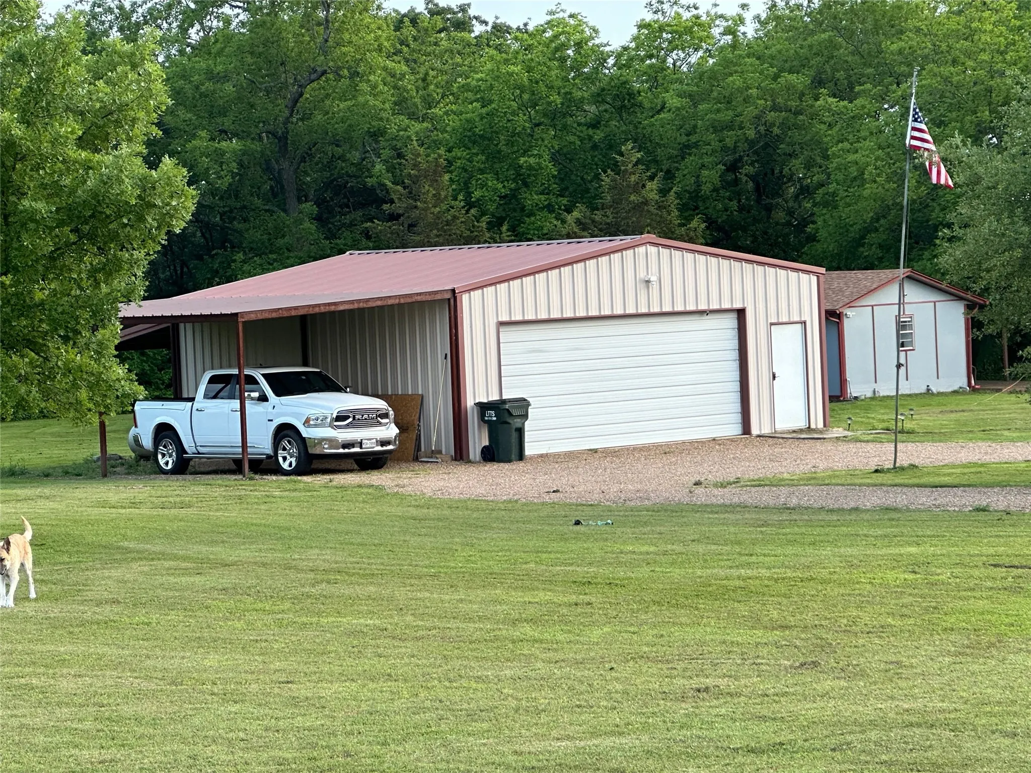 Metal-sided outbuilding with an attached carport, overhead garage door, and side-entry door