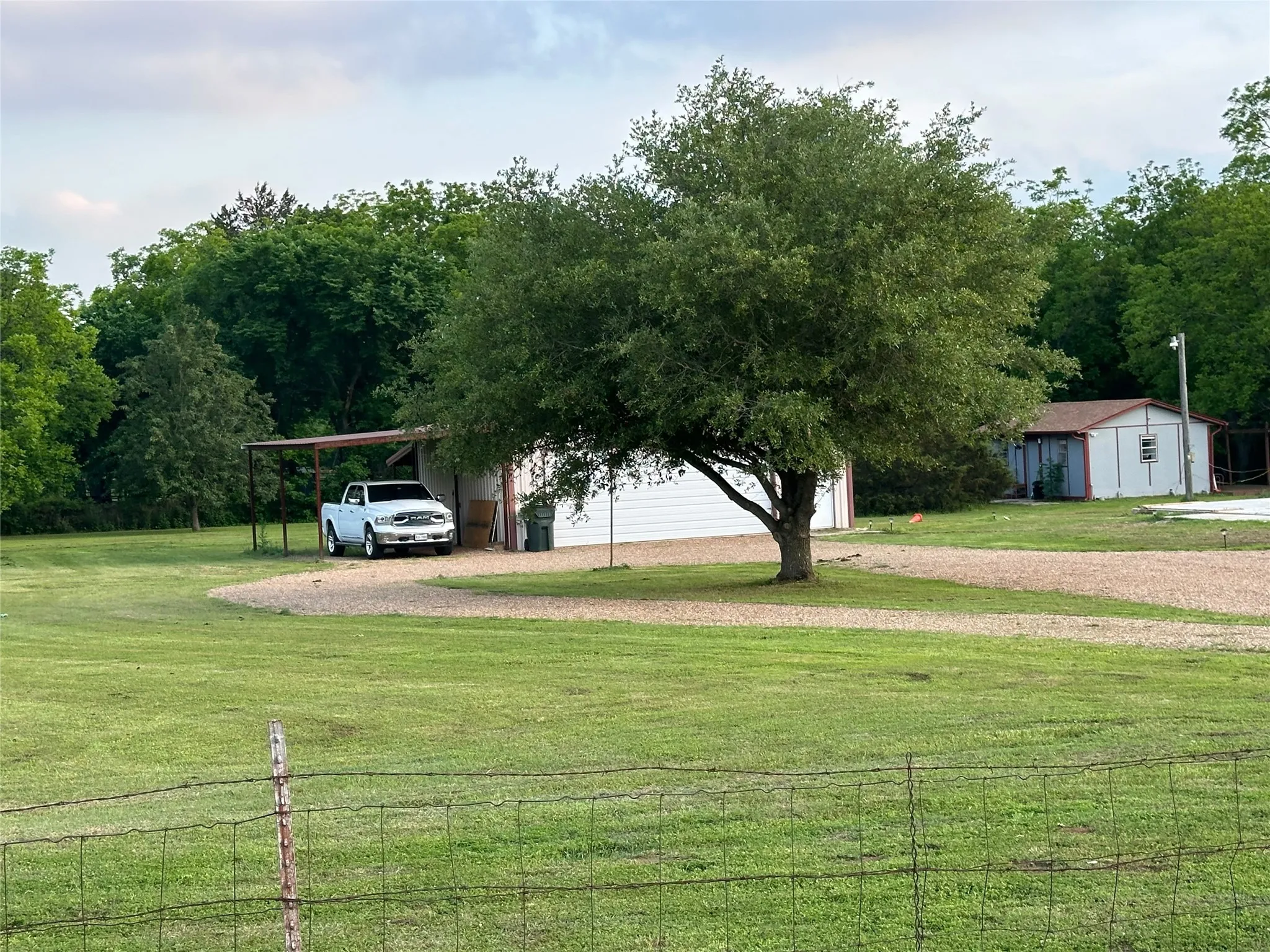 Expansive gravel driveway leading to a metal carport