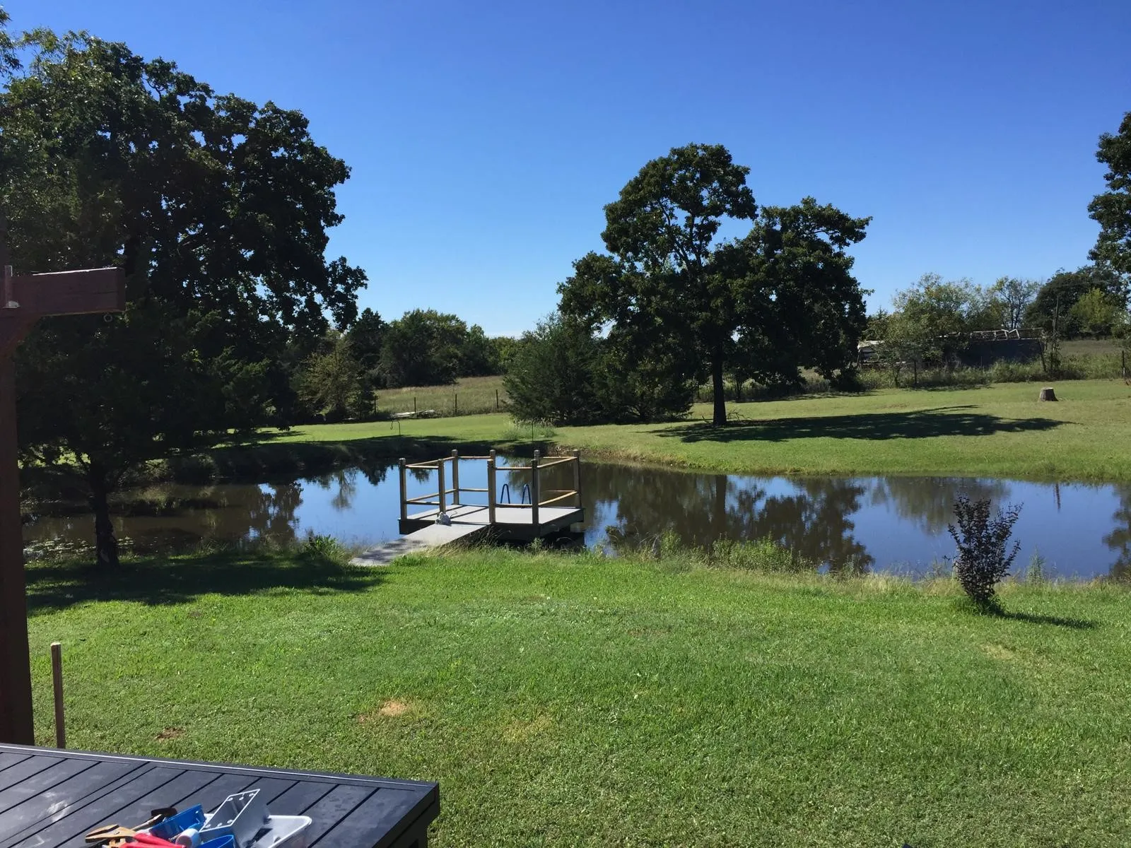 Expansive green lawn with a private pond and a wooden dock