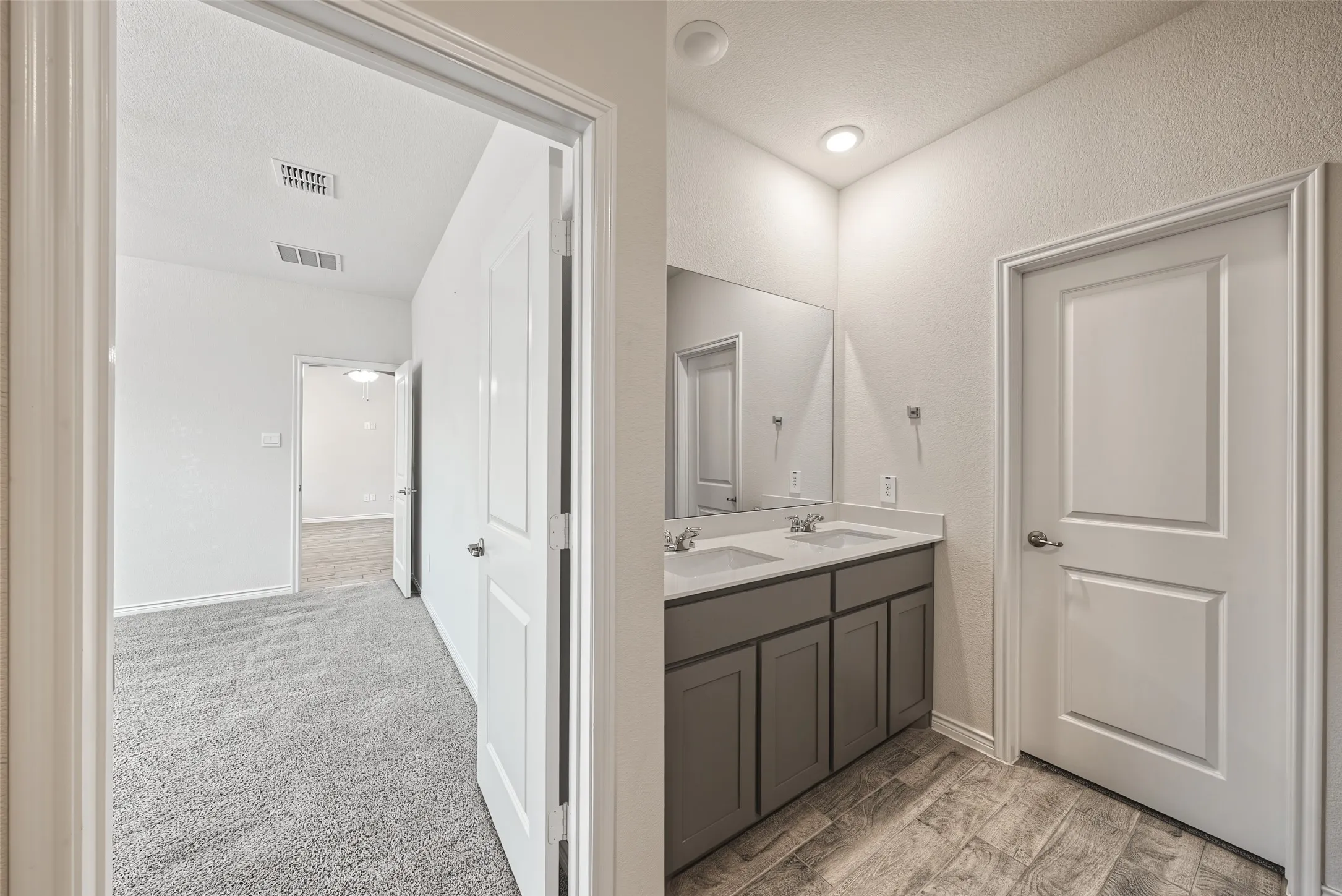 Dual vanity with undermount sinks, porcelain tile flooring, and recessed lighting