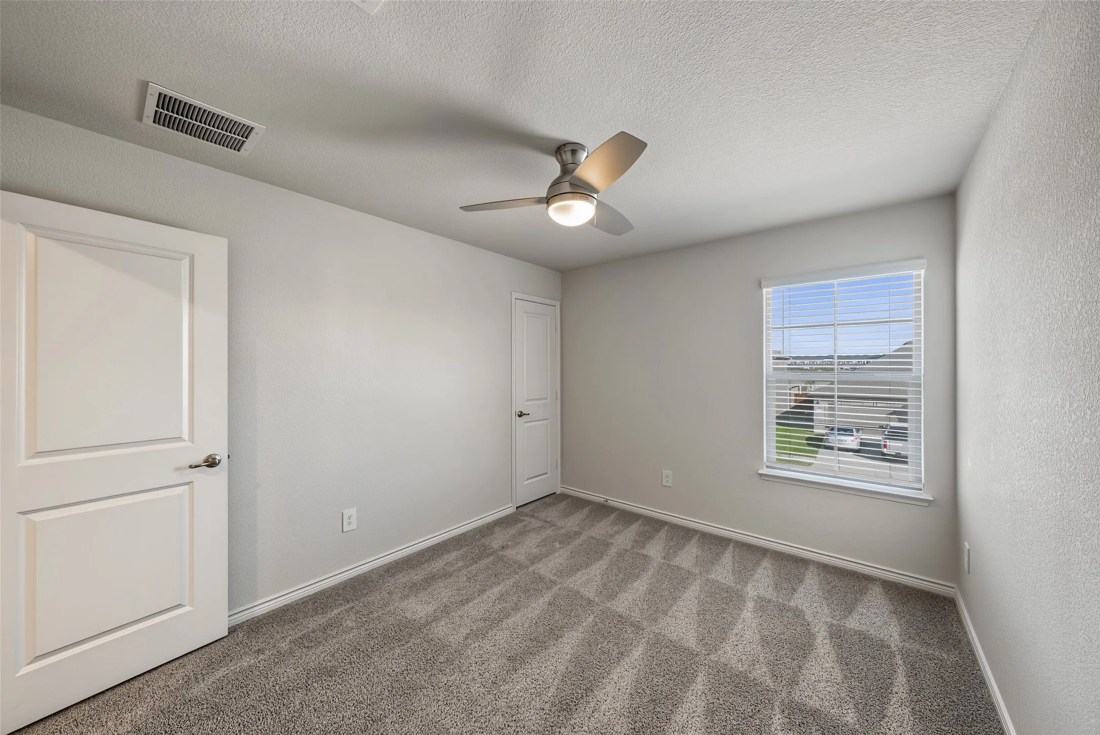 Neutral-toned room, carpet flooring, a ceiling fan with integrated lighting, and a window with blinds
