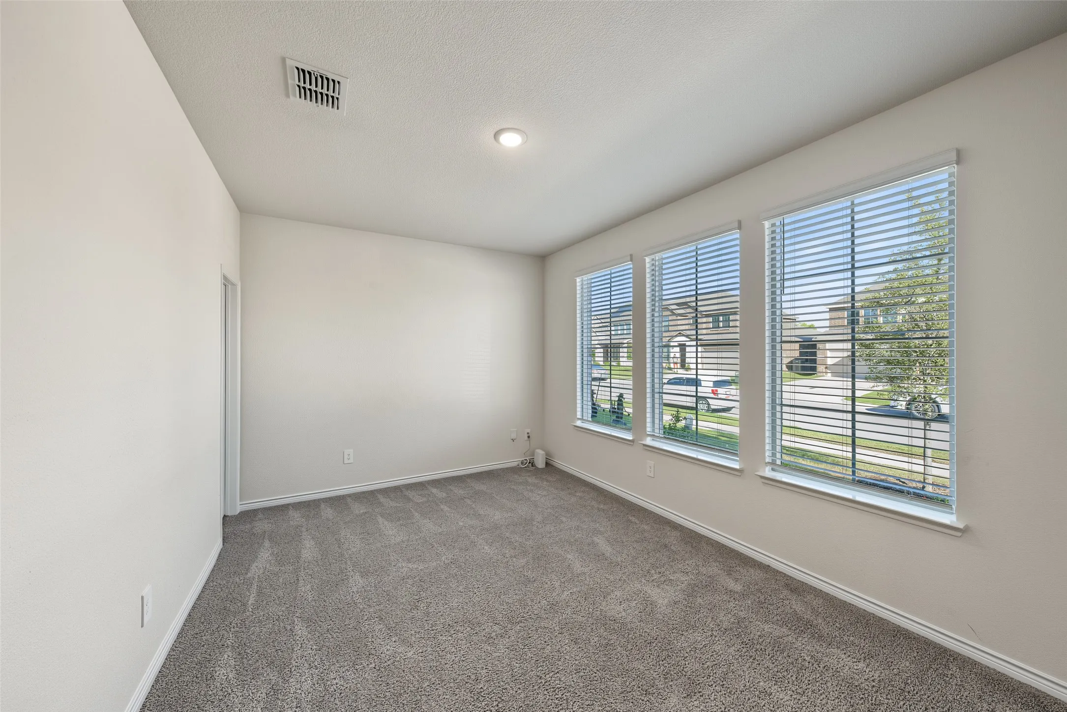 Carpeted room featuring three windows with blinds, recessed ceiling lighting, and a white ceiling