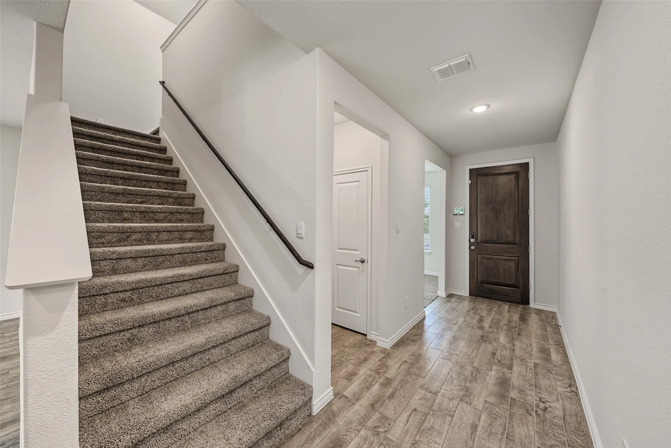 Entryway featuring porcelain tile flooring, a dark wood-paneled door, and recessed lighting