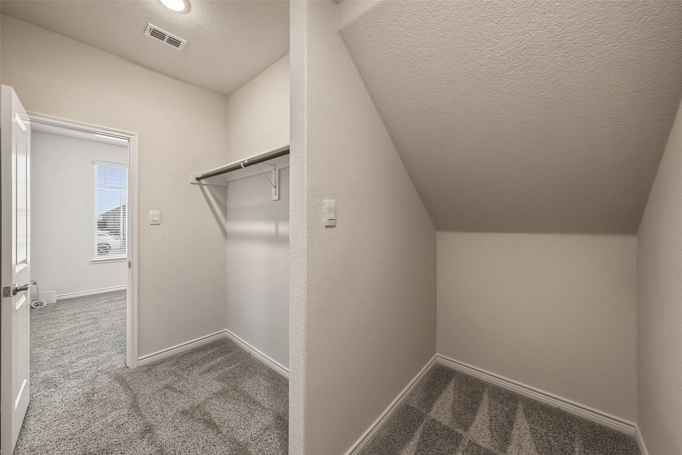 Large office closet is carpeted with shelving, hanging rod, and recessed lighting