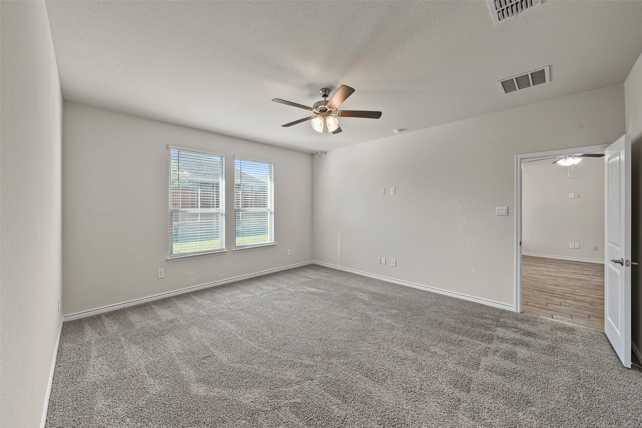 Plush grey carpeting with a ceiling fan and overhead lighting