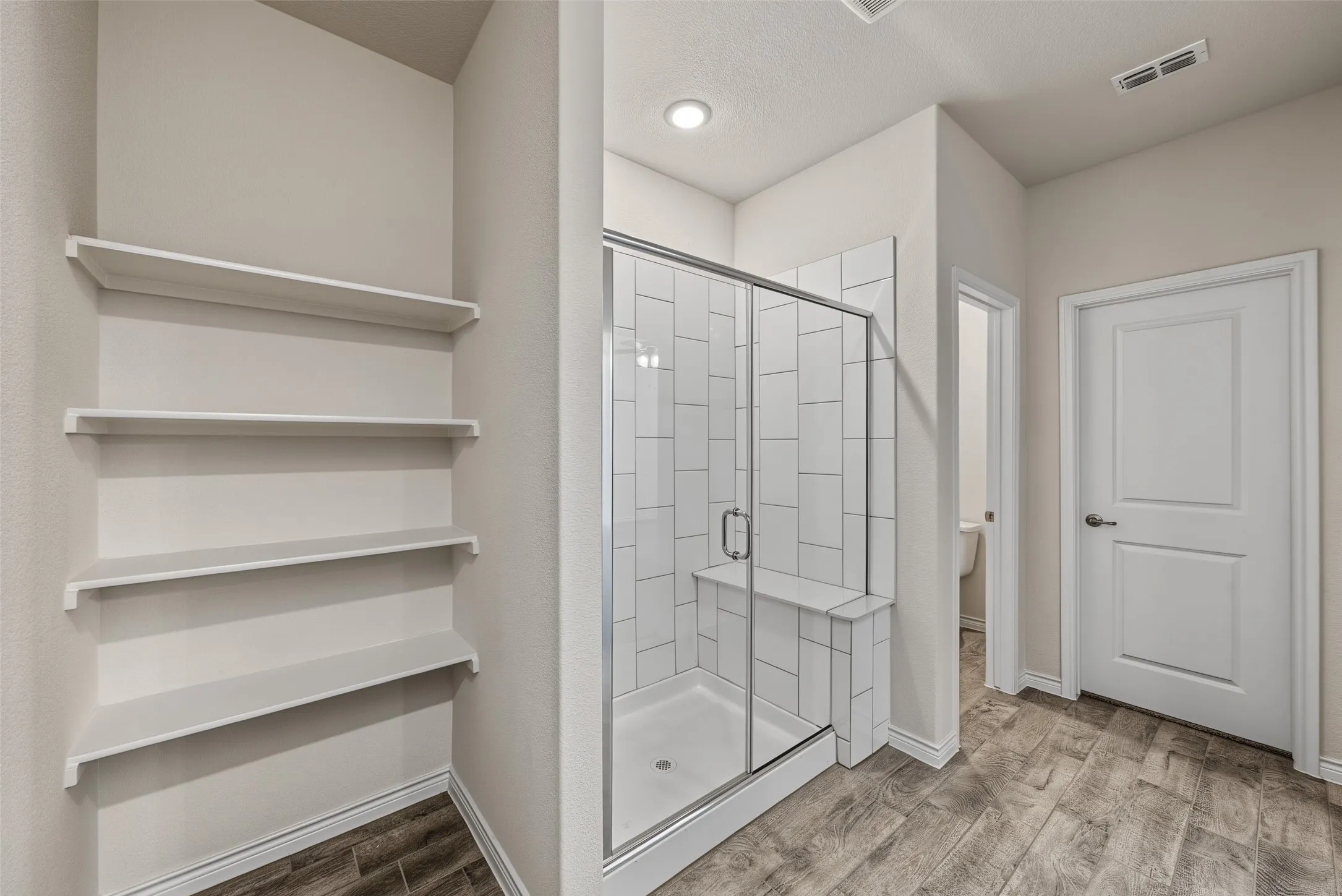 Spacious walk-in shower with vertical tile surround and built-in bench