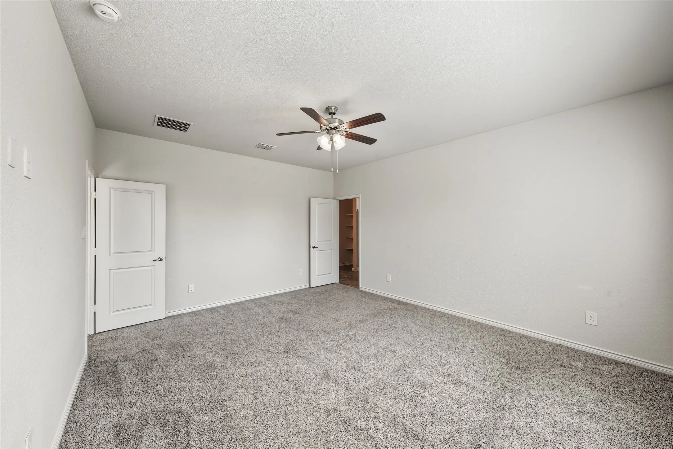 Neutral toned carpeting, contemporary ceiling fan with lighting, and multiple panel doors