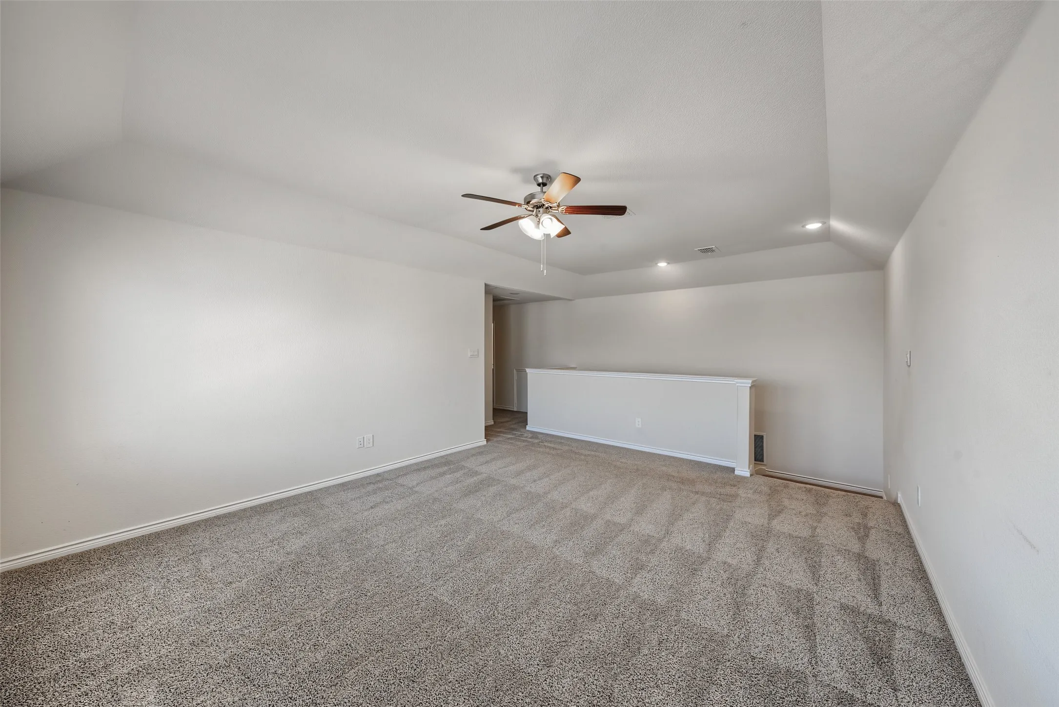  Carpeting throughout, vaulted ceiling, recessed lighting, and a ceiling fan with light