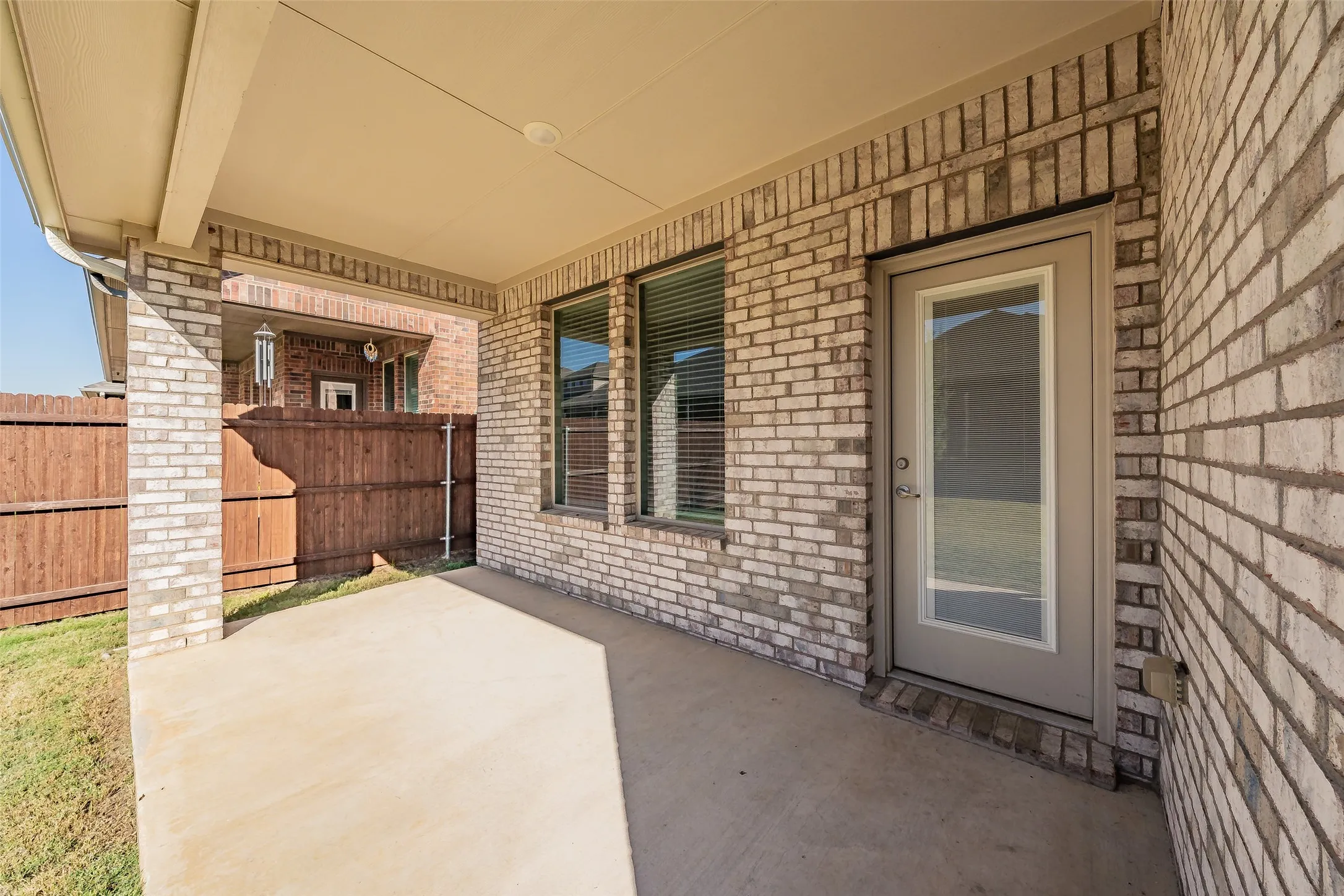 Covered back patio featuring a concrete slab and brick columns