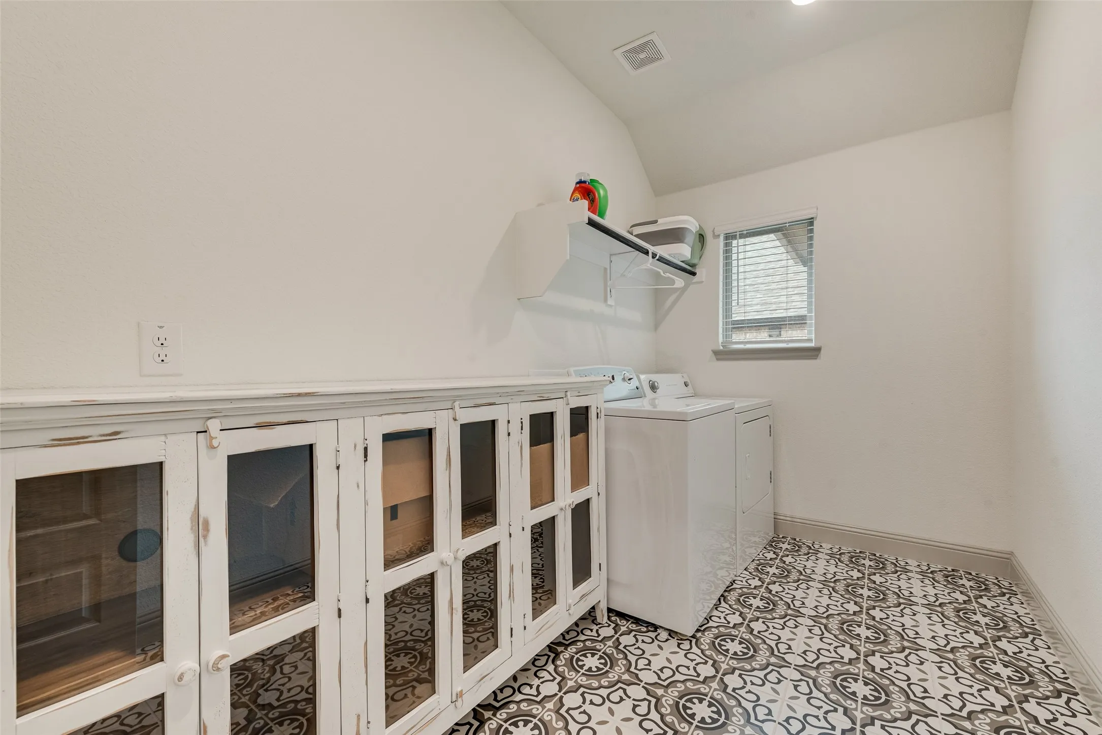 Patterned tile flooring, white walls, window with blinds, recessed lighting, and a wall-mounted shelf