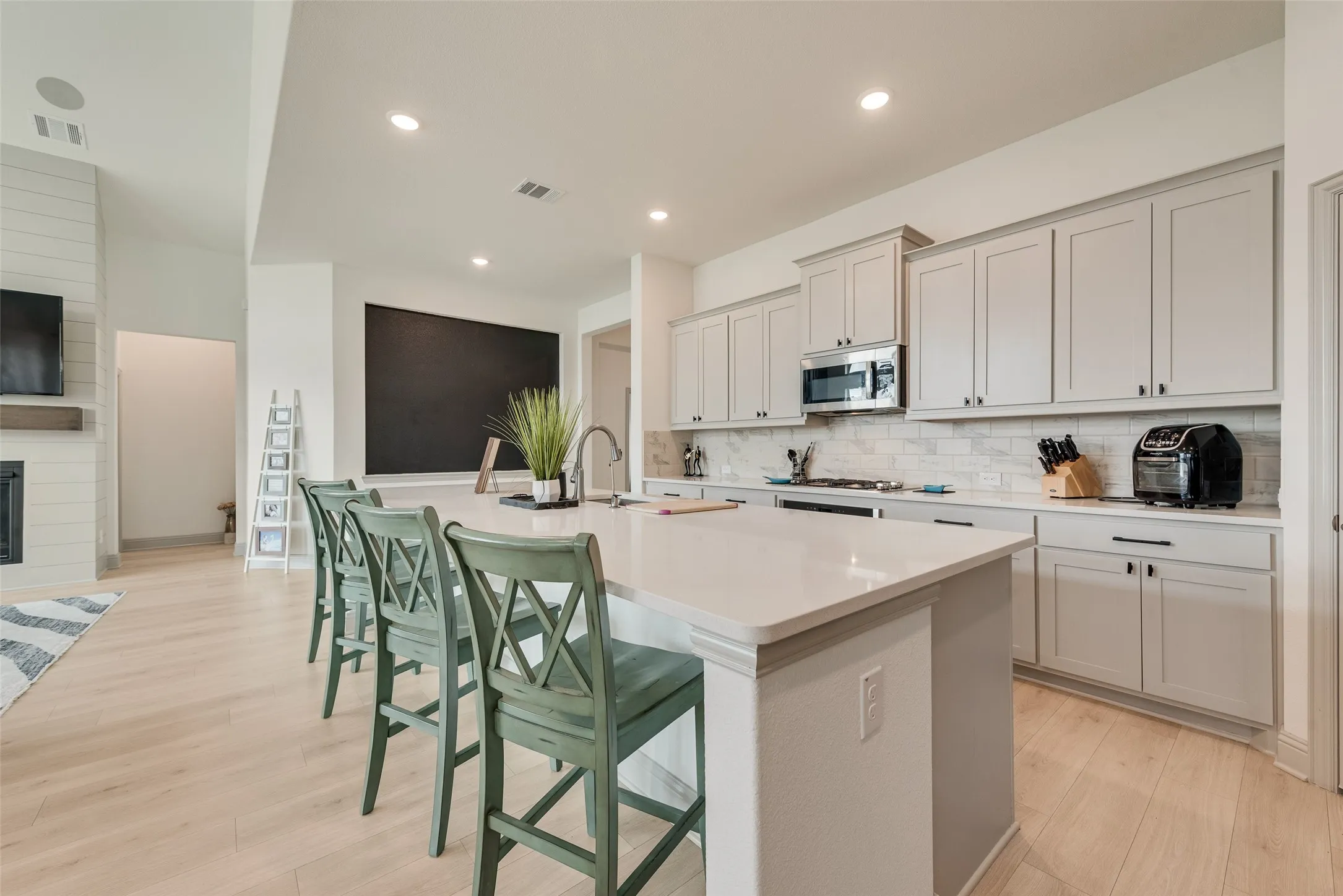 Spacious kitchen island with a light-toned countertop, light-toned cabinetry, stainless steel appliances, and wood-finish flooring