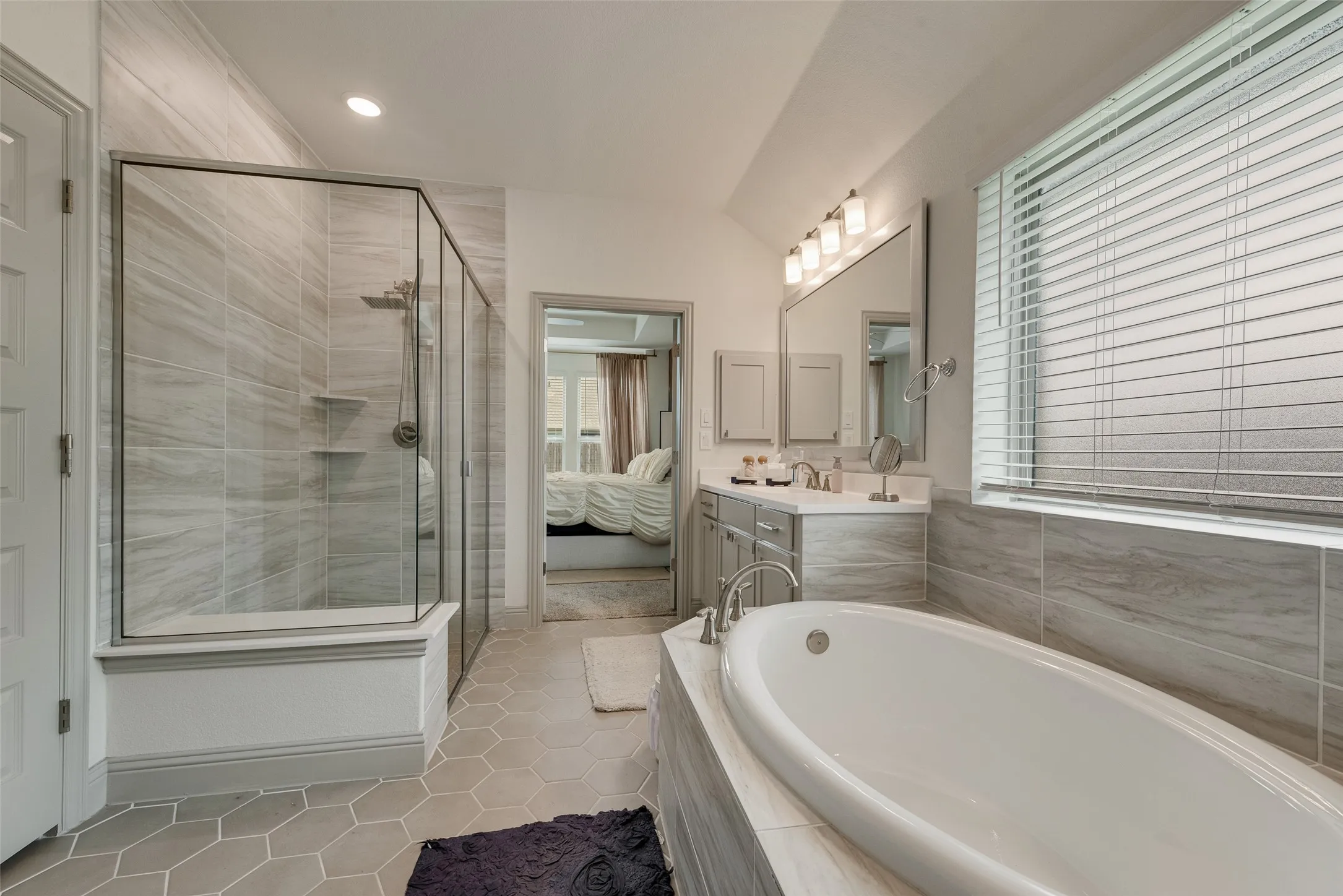 Glass-enclosed tiled shower and a separate soaking tub in the primary bathroom
