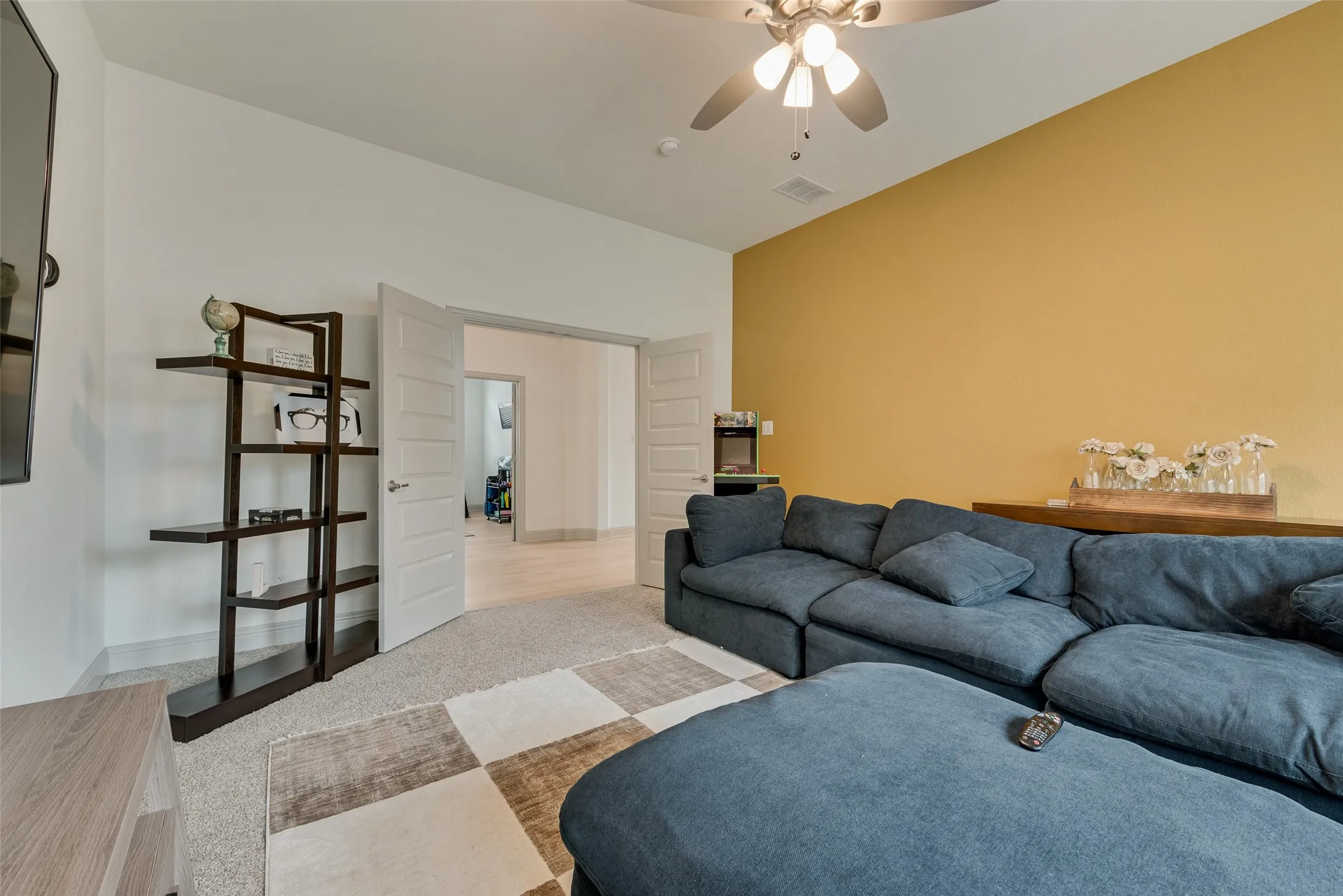 Game room with a ceiling fan, carpeted flooring, and a warm accent wall